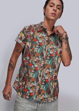 S=Person wearing a colorful floral patterned shirt against a plain background