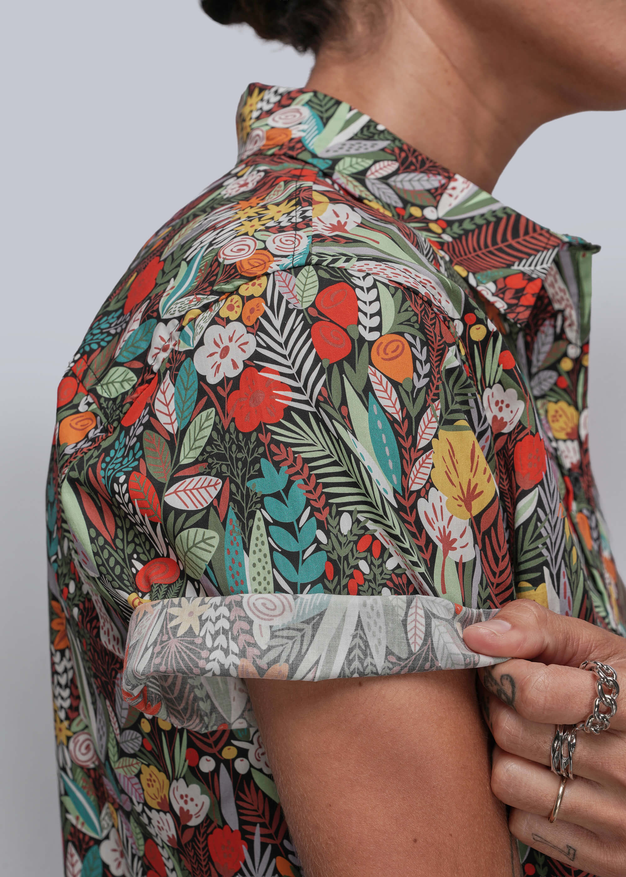 Person wearing a colorful floral patterned shirt against a plain background