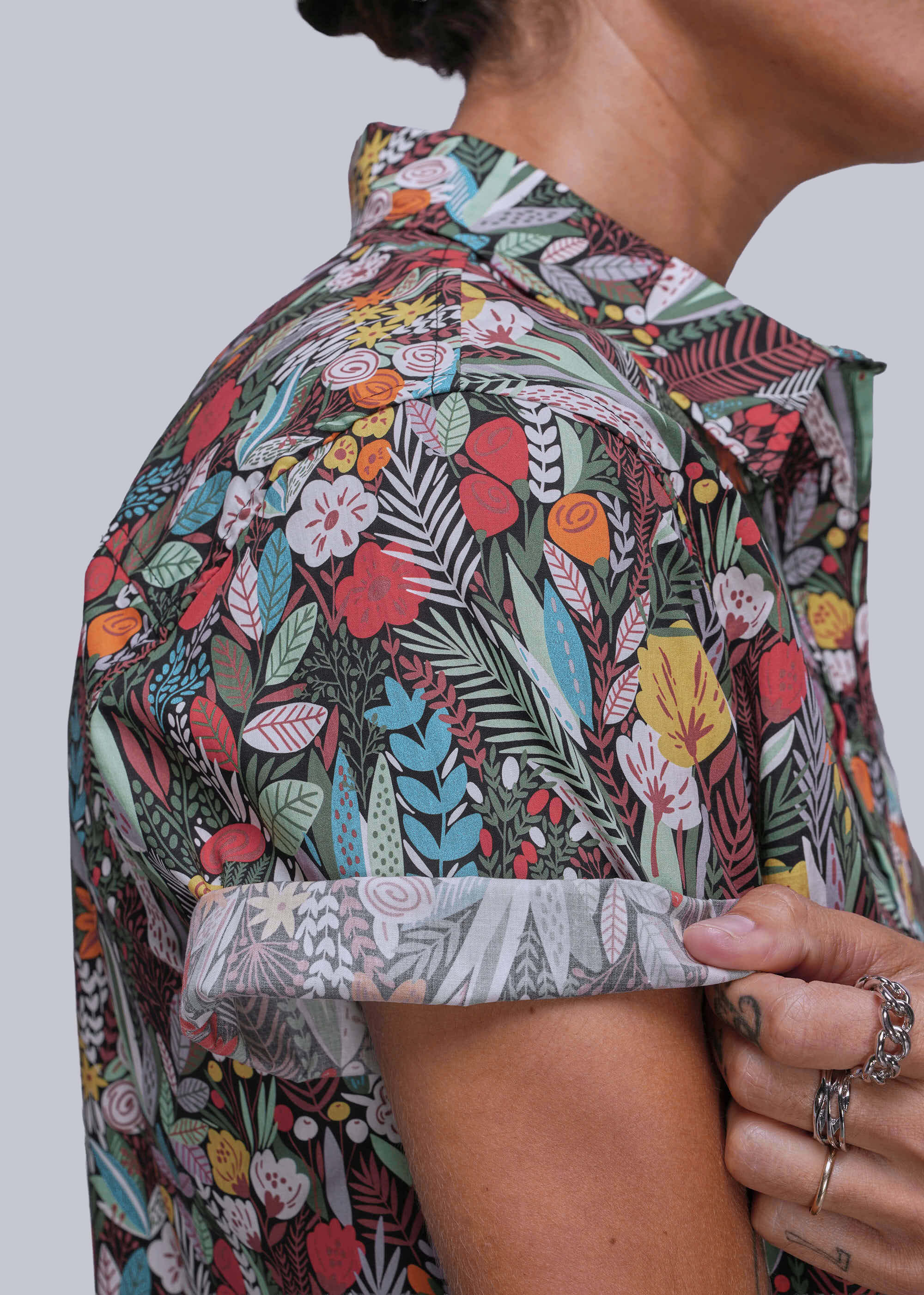 Person wearing a colorful floral patterned shirt against a plain background