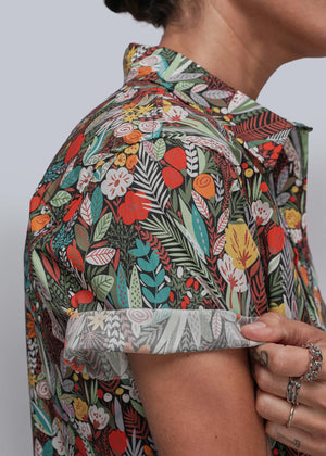 S=Person wearing a colorful floral patterned shirt against a plain background
