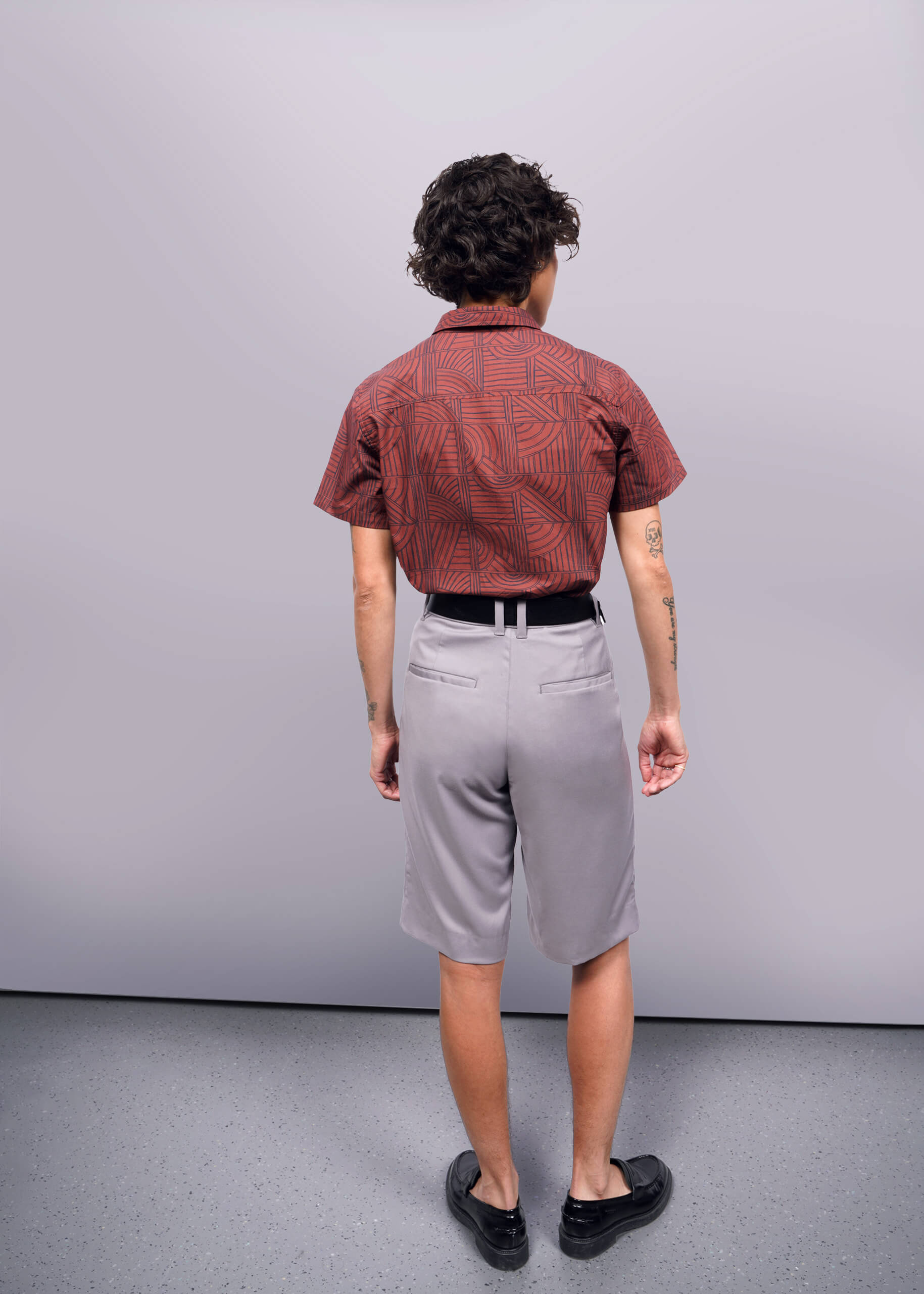 S=Back of person wearing The Essential Button Up in Terrace Cinnamon Navy and grey shorts against neutral background