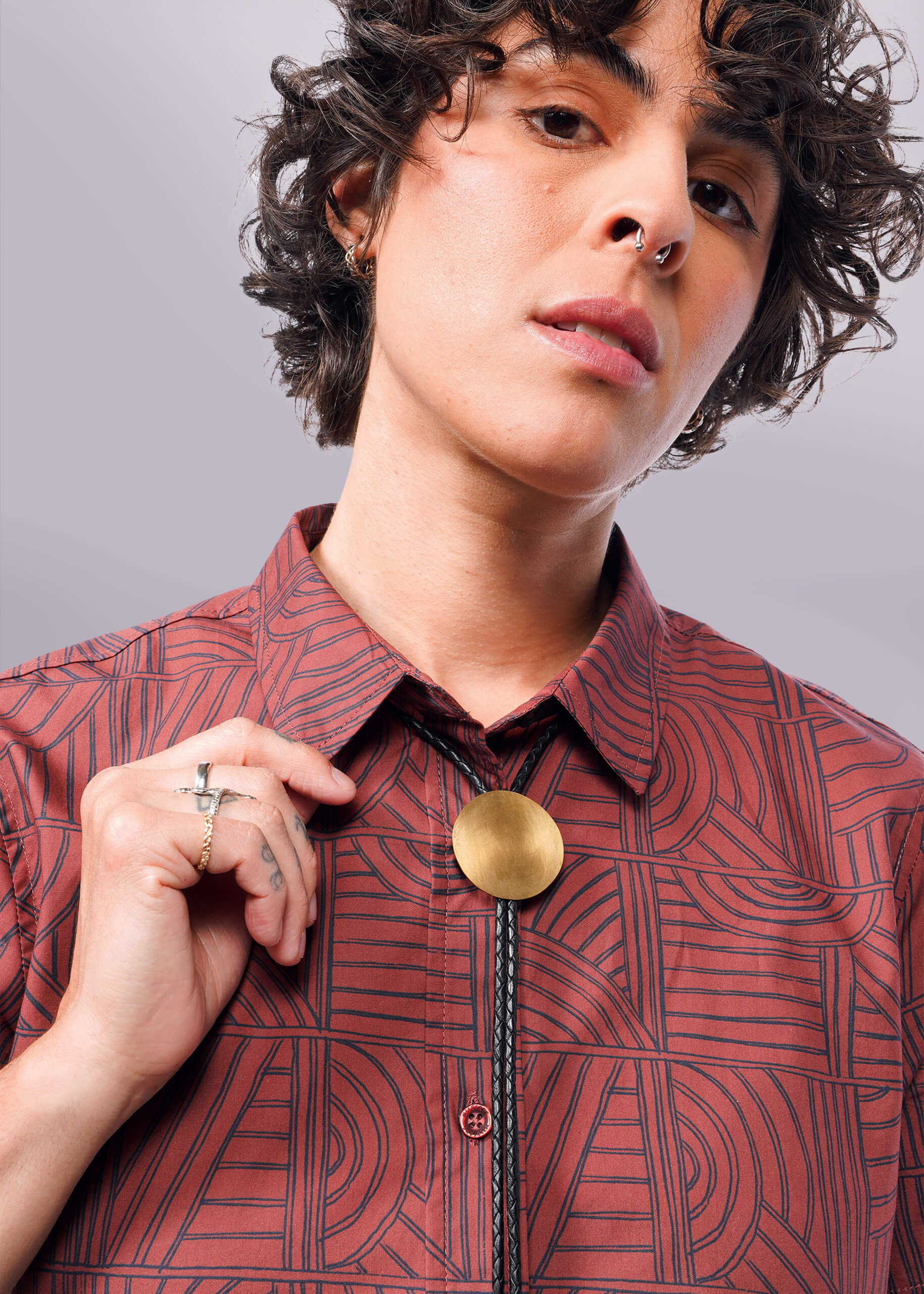 Close up of person holding collar of The Essential Button Up in Terrace Cinnamon Navy against neutral background.