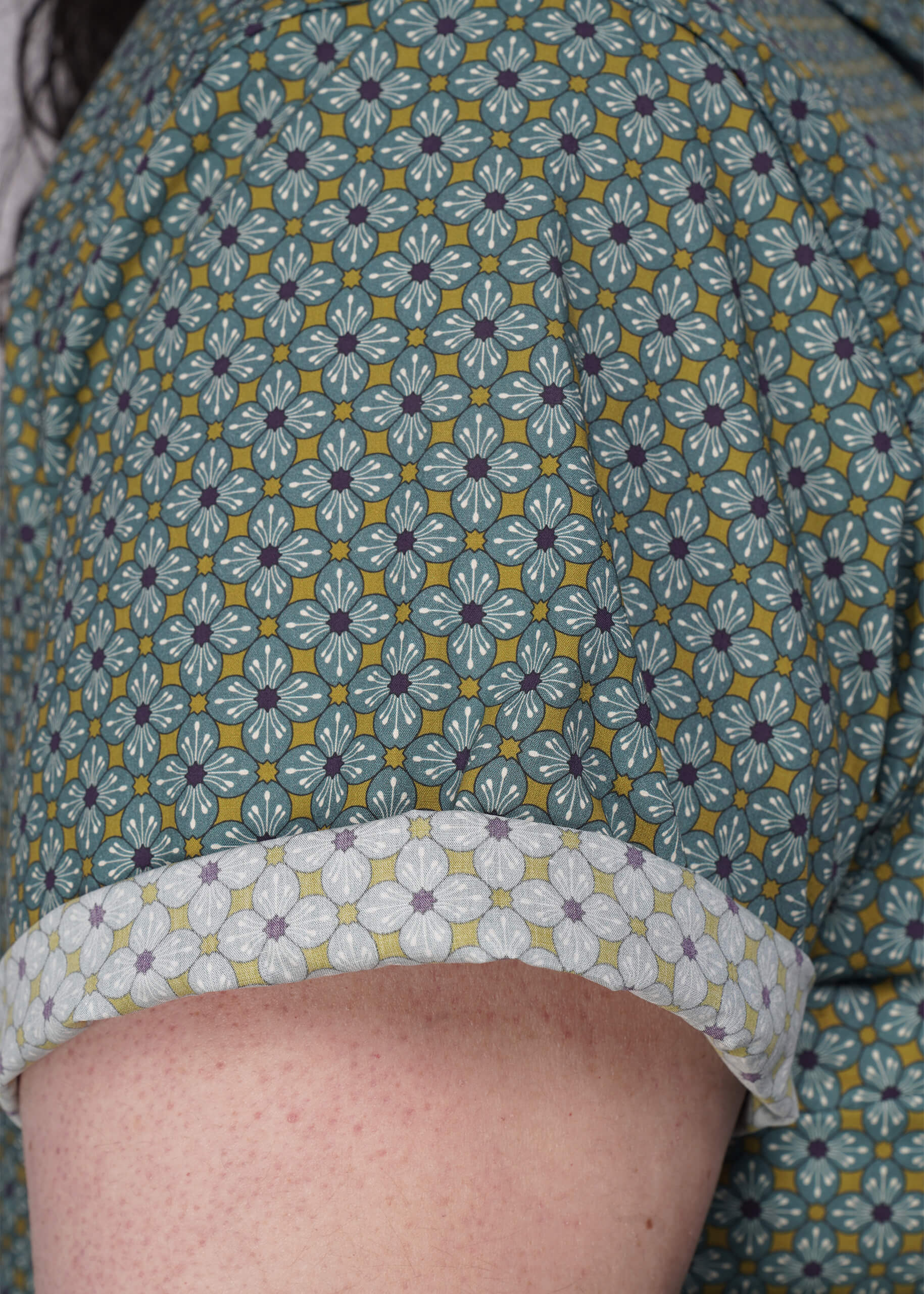 1X=Close-up of a patterned shirt sleeve that a person is wearing