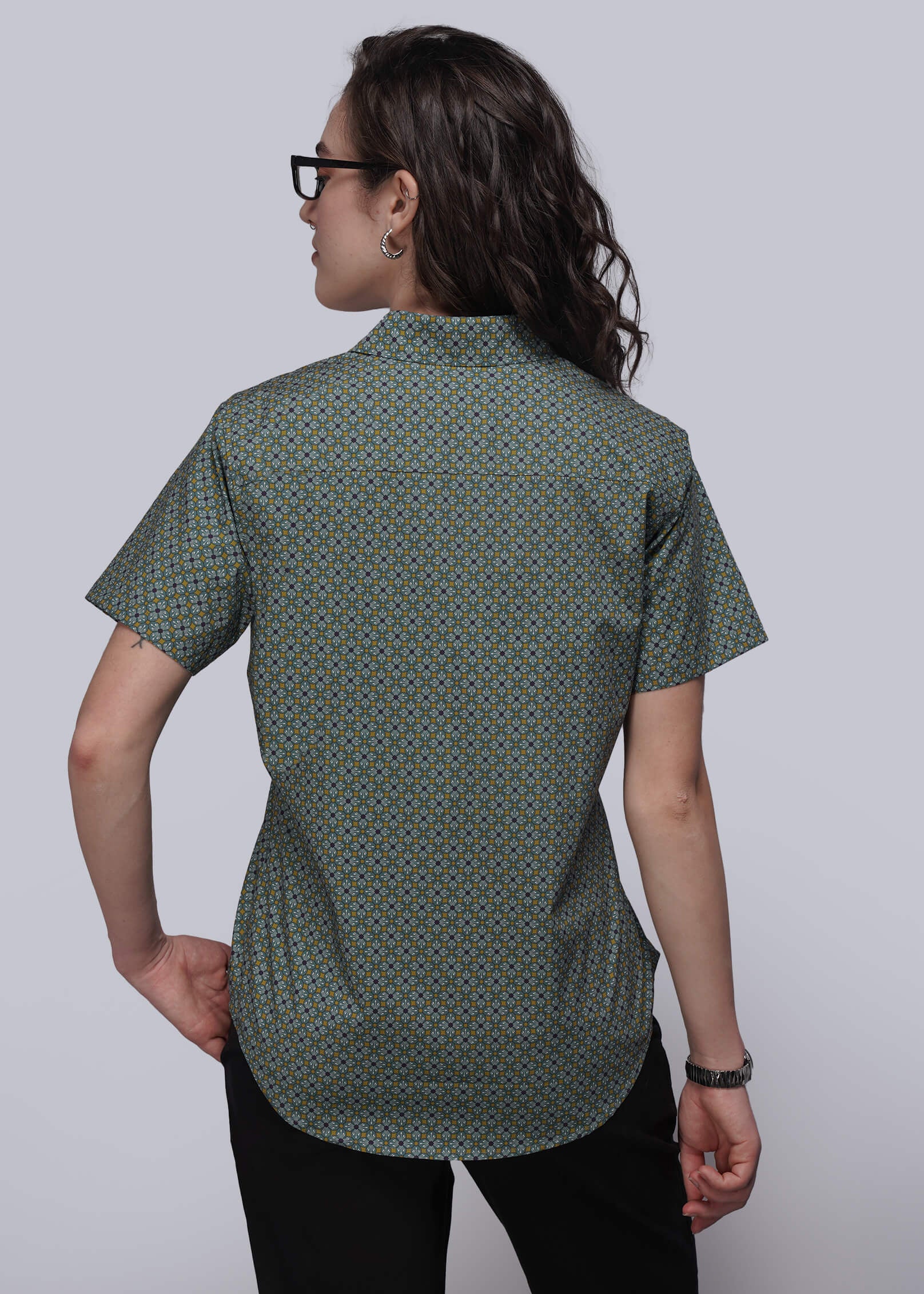 S=\Person wearing a green patterned shirt against a plain background\\