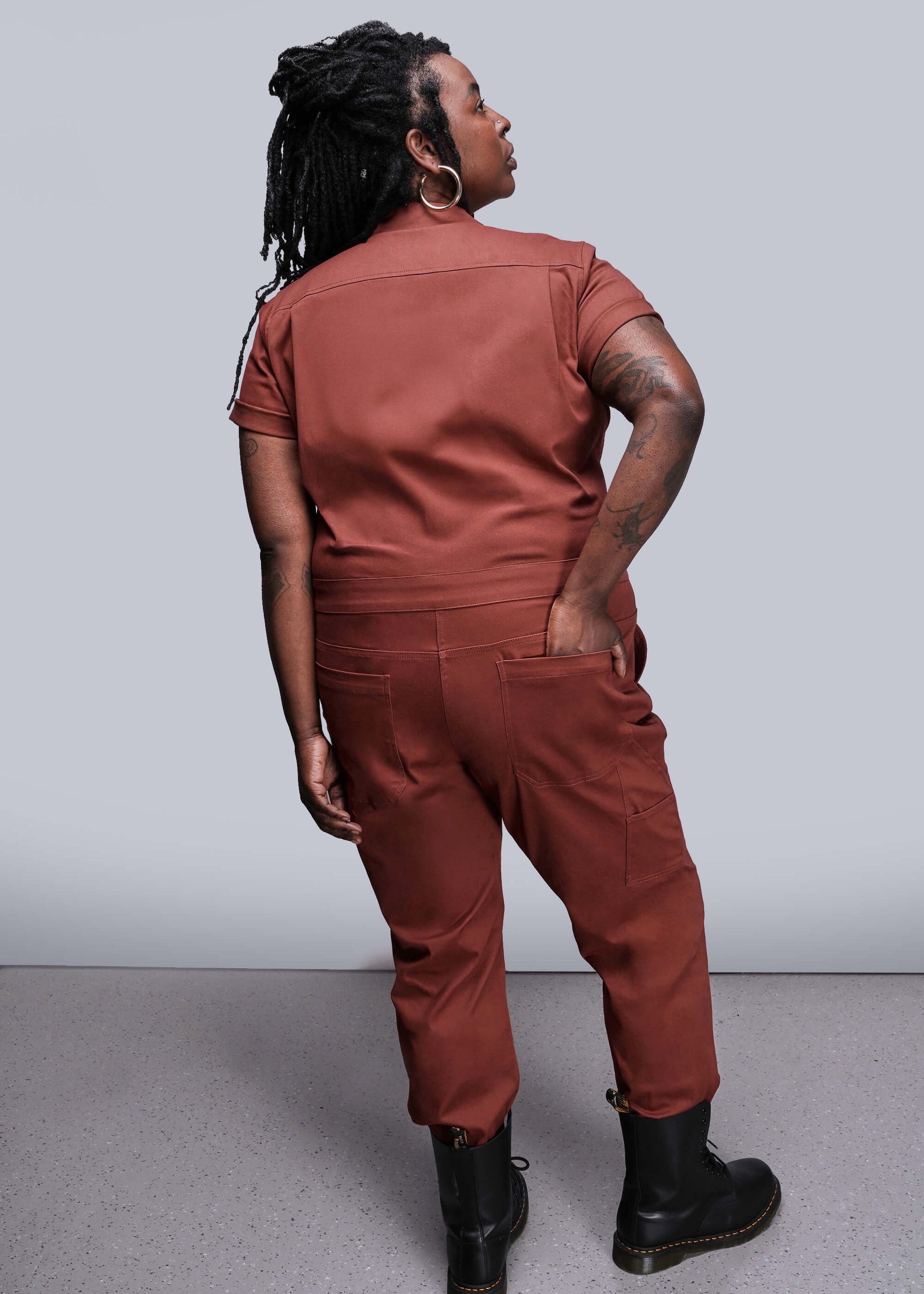 1X=Person wearing an orange brown jumpsuit against a white background