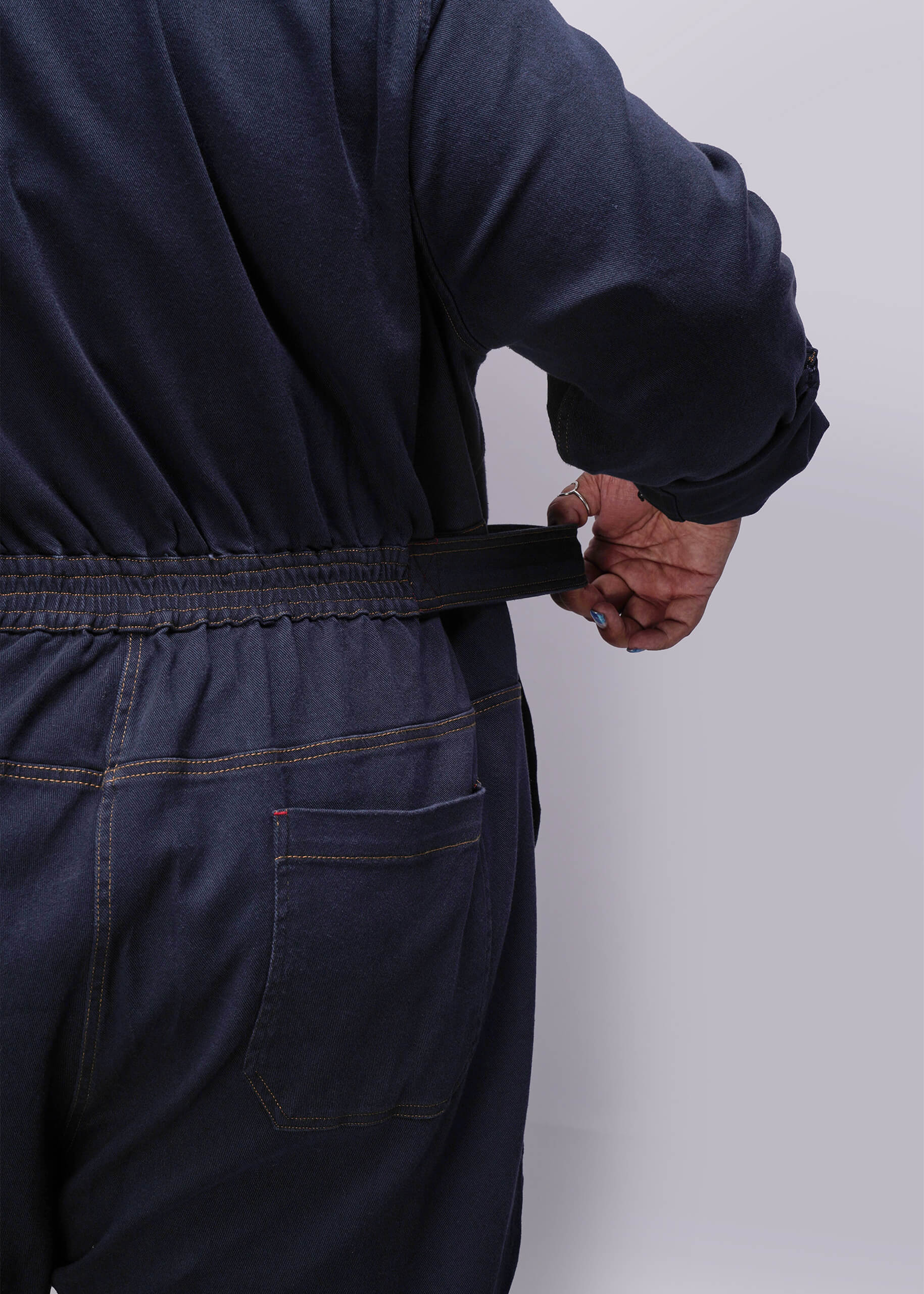 1X=Person wearing a navy blue denim jumpsuit against a grey background