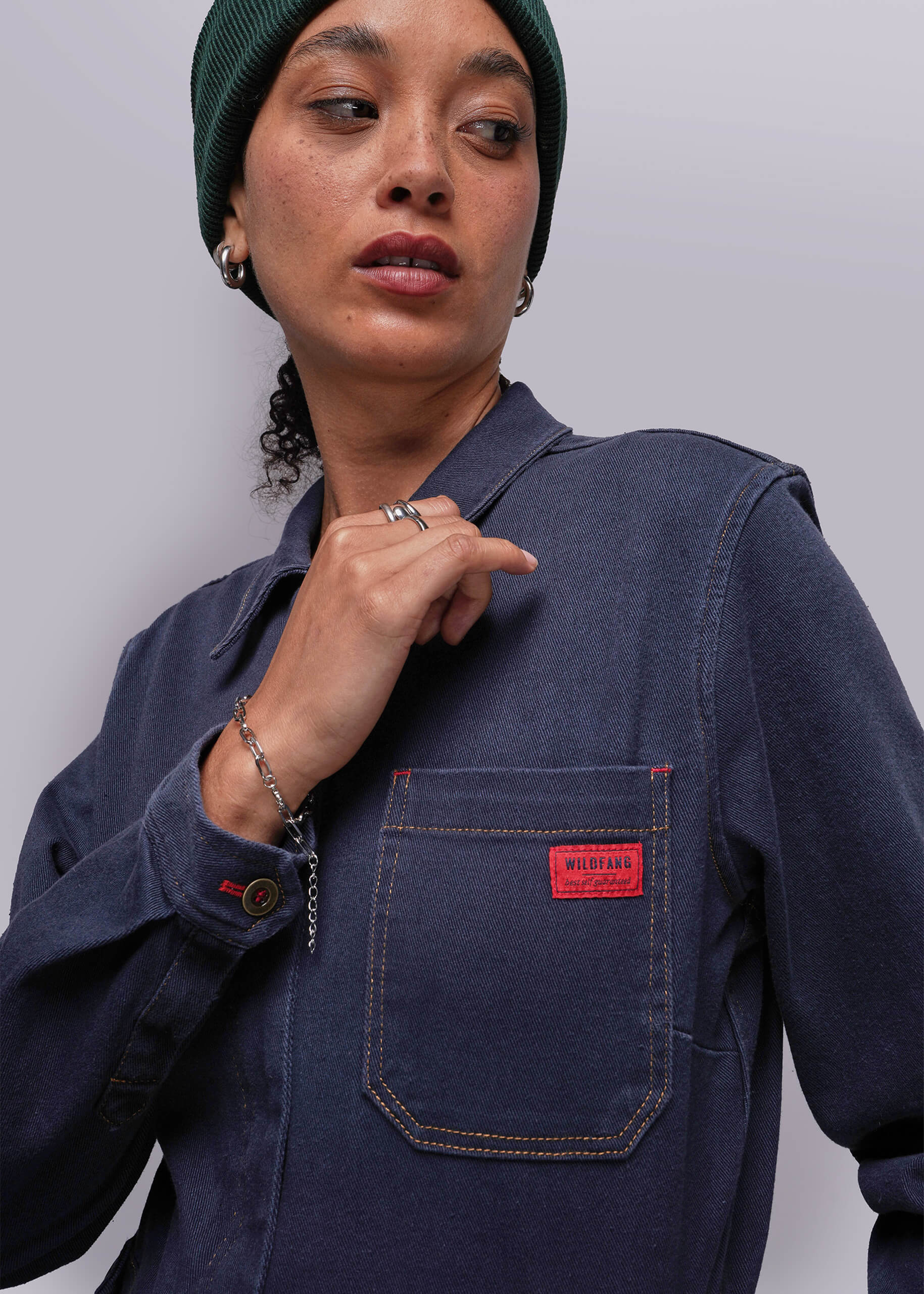 Person wearing a navy blue jacket with a red pocket patch on a plain background