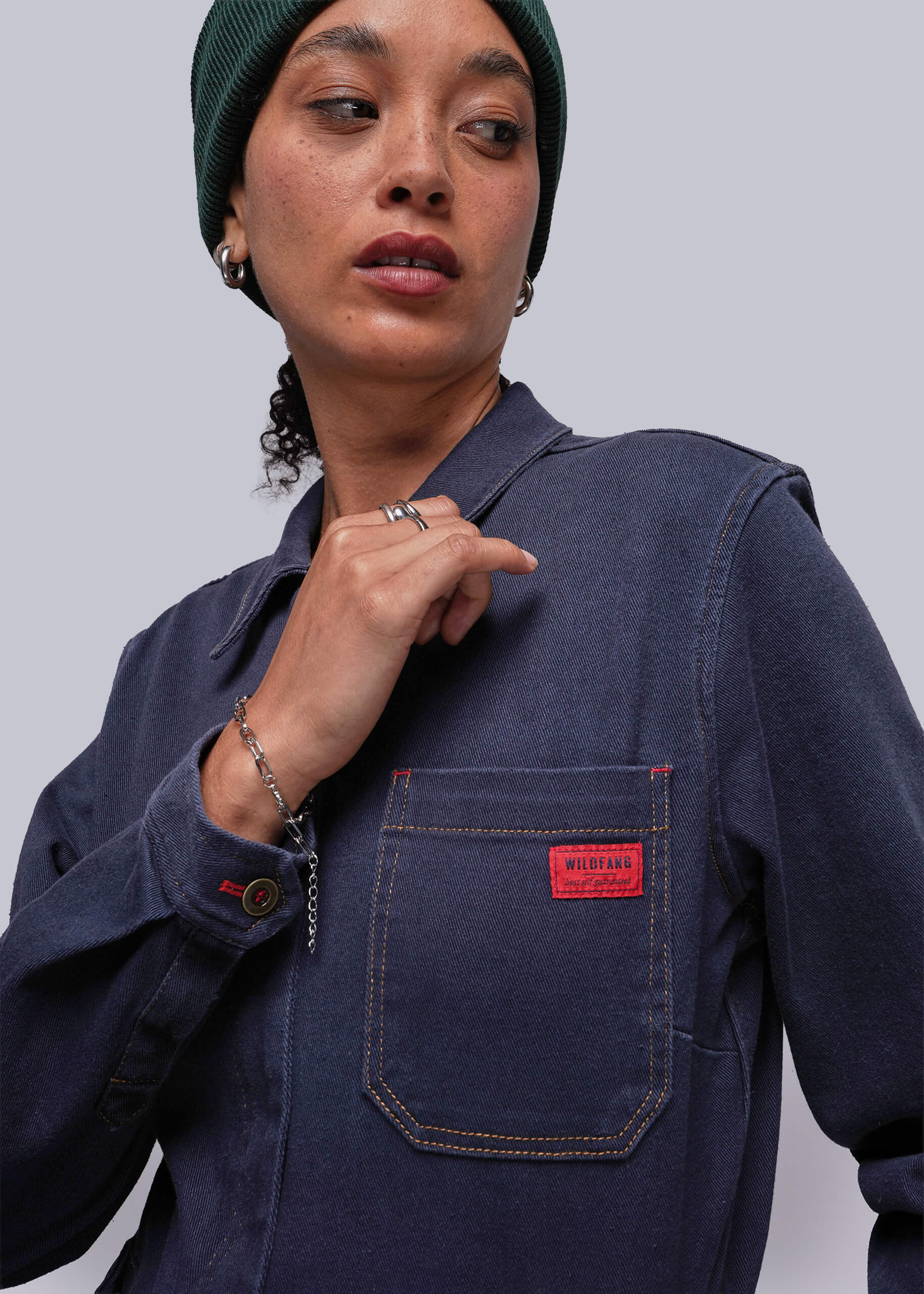 Person wearing a navy blue jacket with a red pocket patch on a plain background