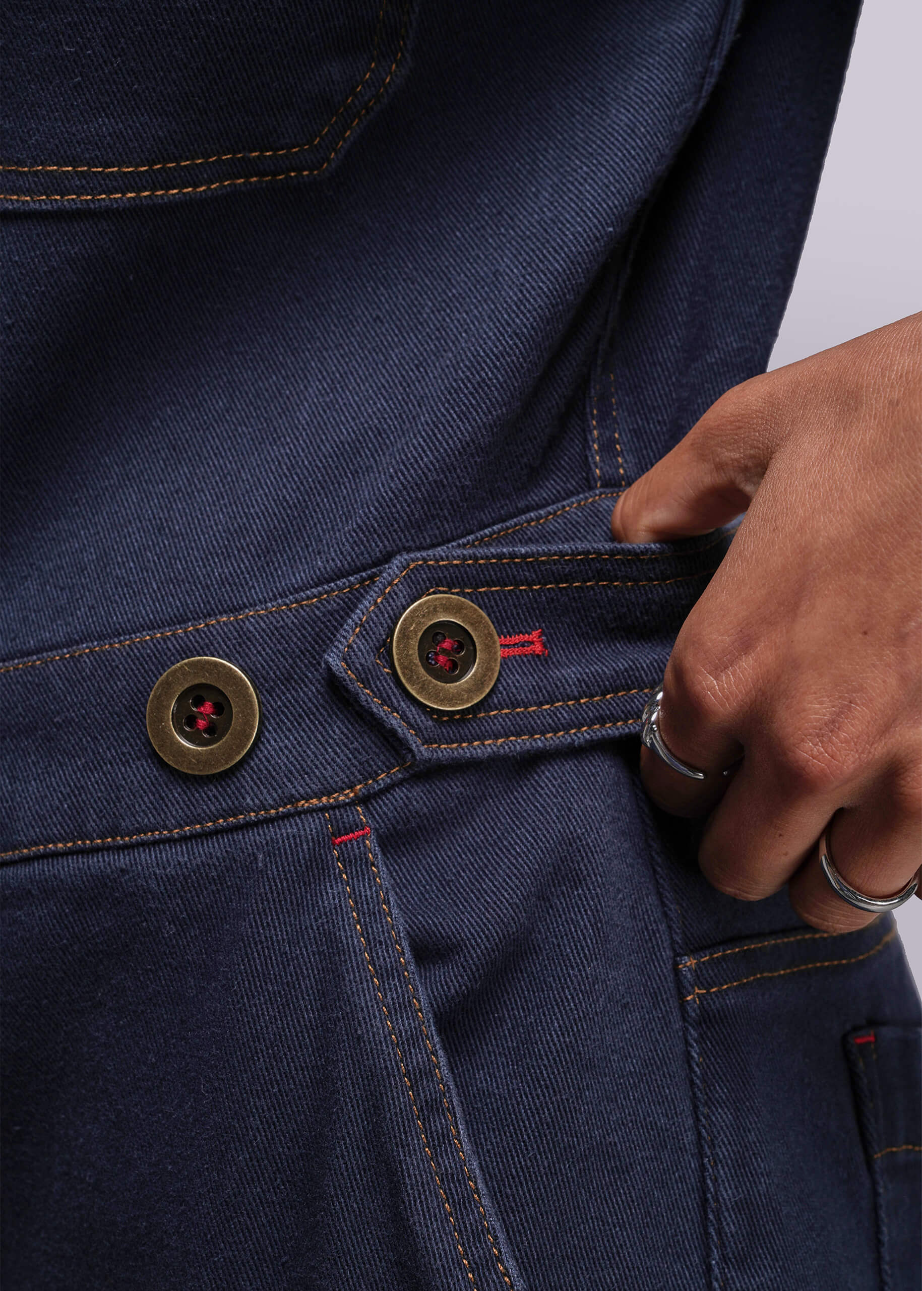 S=Close-up of a person wearing blue denim jumpsuit with gold buttons.