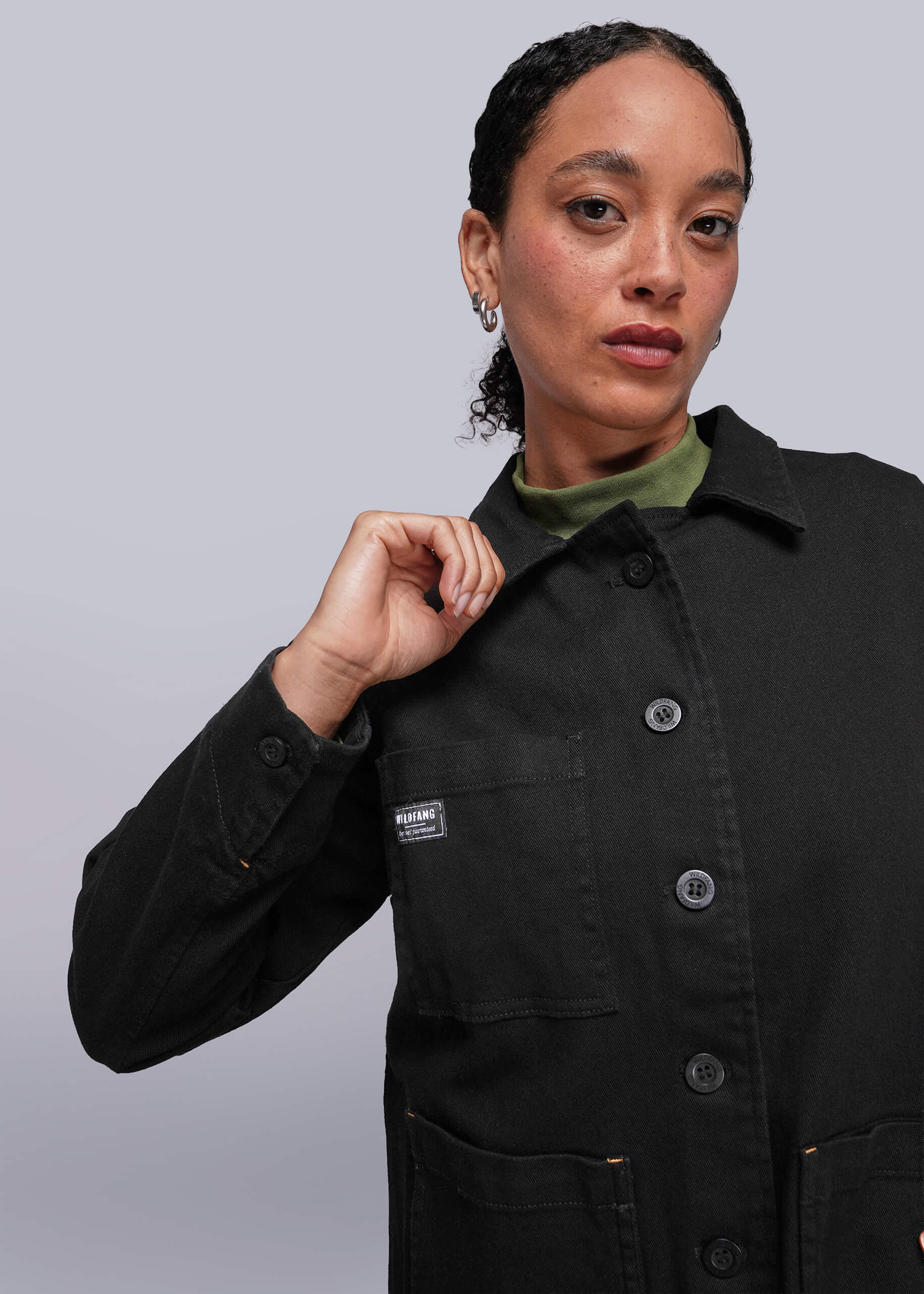 Person wearing a black jacket with a brand logo on a light gray background