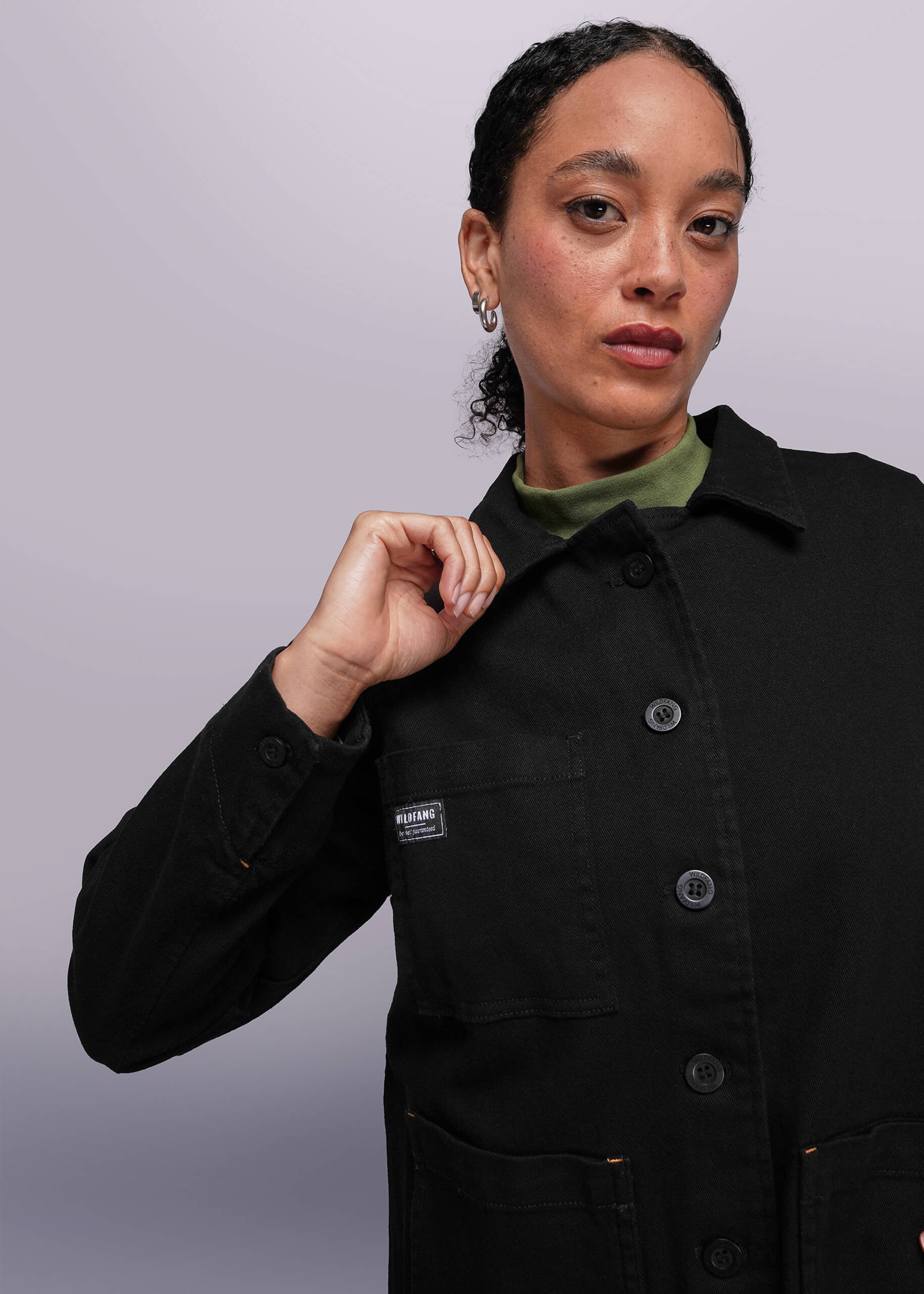 S=Person wearing a black jacket with a brand logo on a light gray background