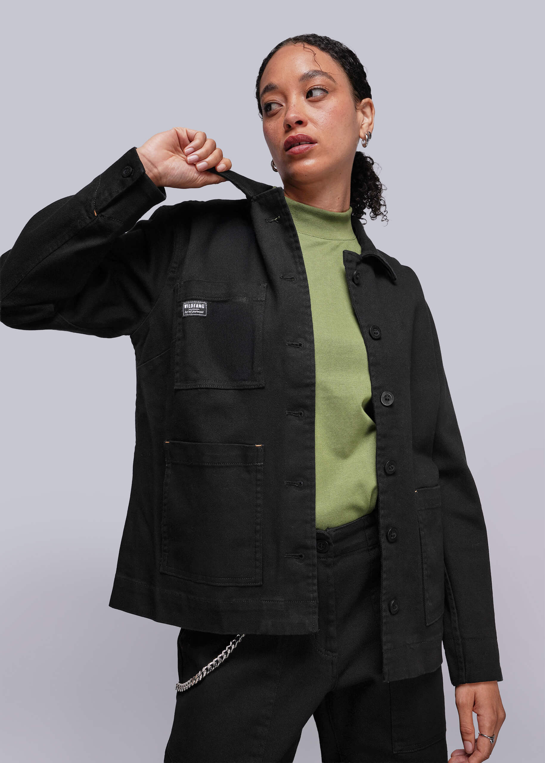 Person wearing a black denim jacket with a visible brand logo on a plain background