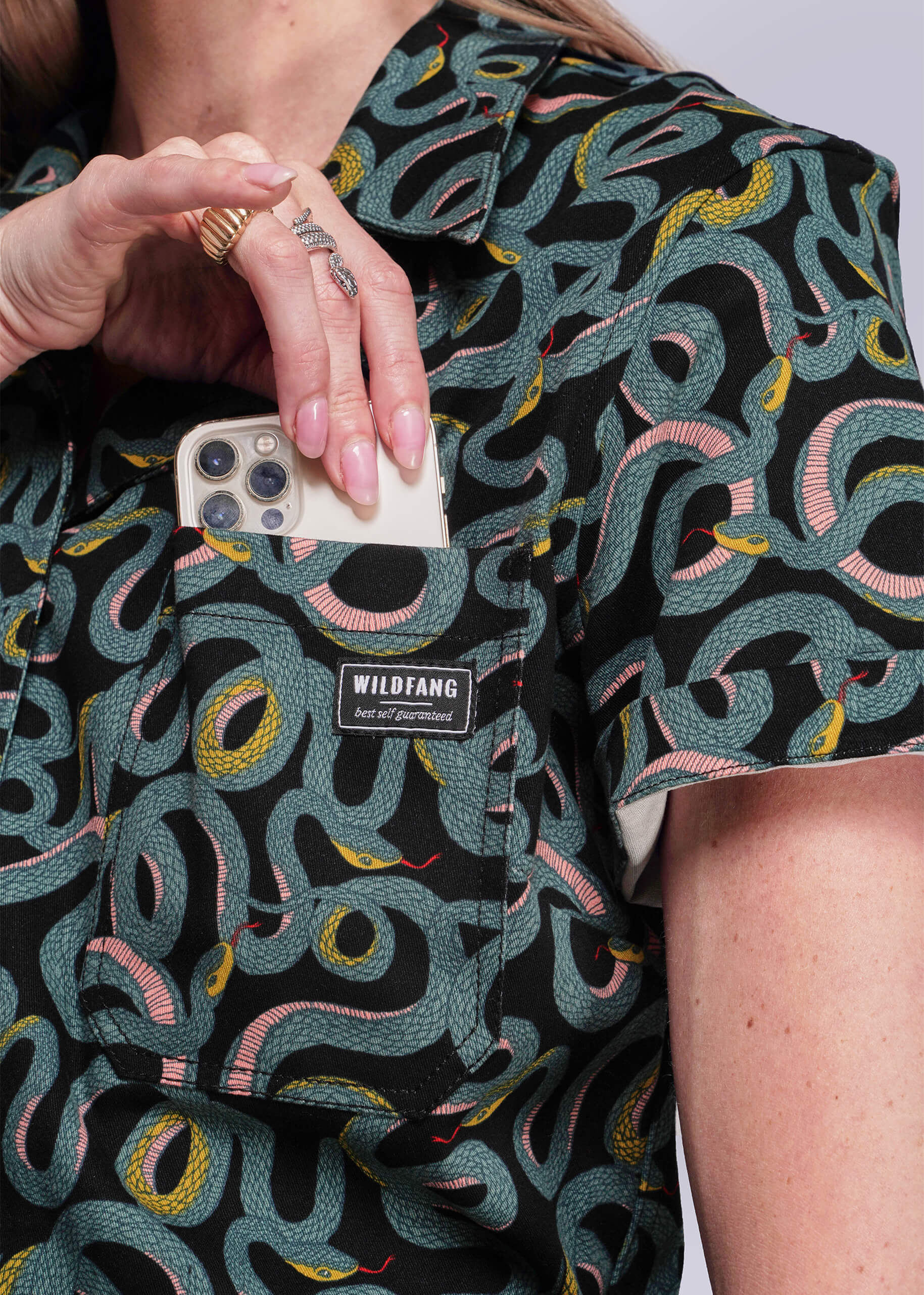 S=Person wearing a patterned shirt with a visible brand label, holding a phone.