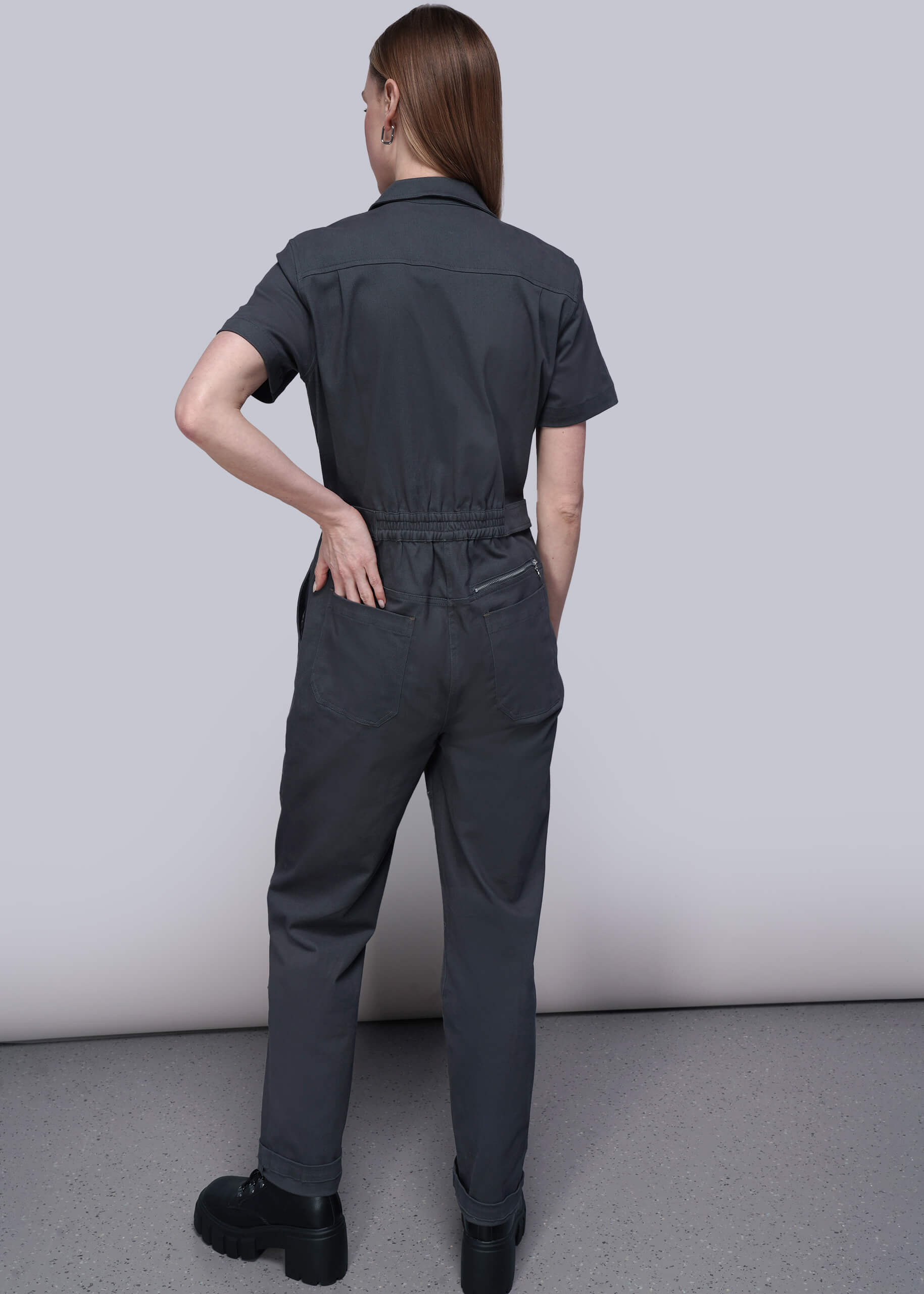 S=Person wearing a dark gray jumpsuit against a plain background