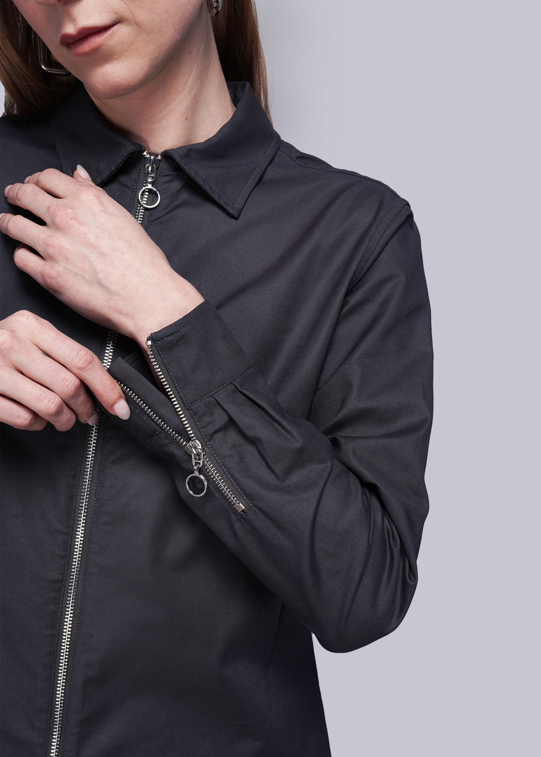 Close up of person wearing a black zip up shirt showing zipper detail on cuffs