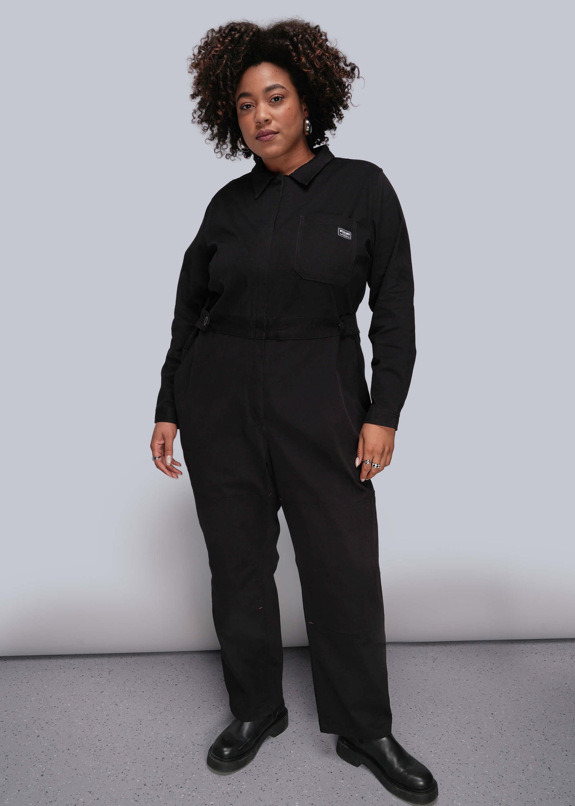 1X=Person wearing a black jumpsuit against a plain background