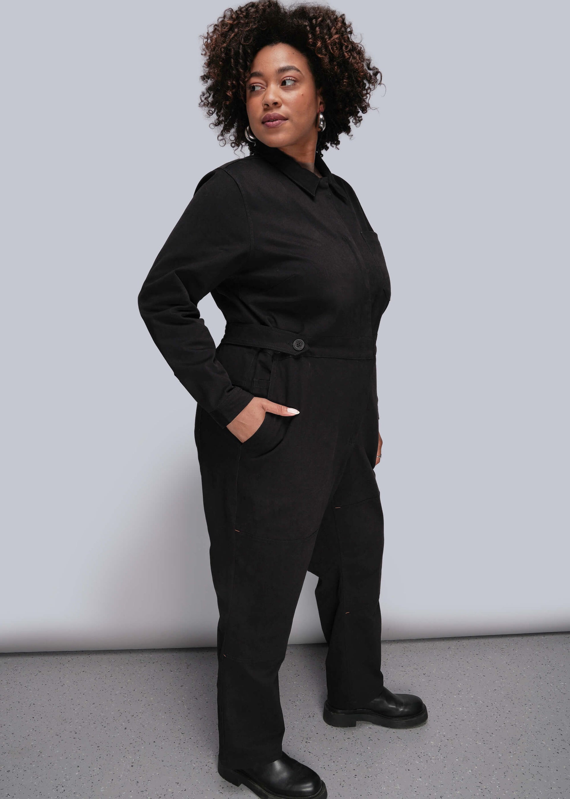 1X=Person wearing a black jumpsuit against a plain background
