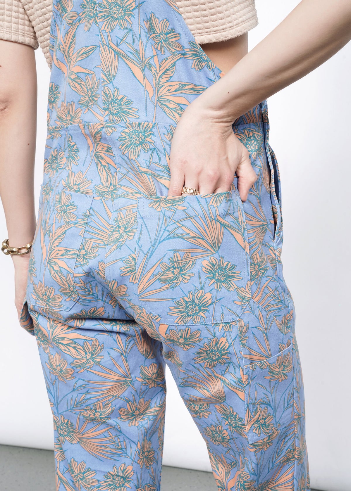 Close-up of Model wearing the Essential Overall in Flower Press Periwinkle in size S wearing tan T, with hand in back pocket