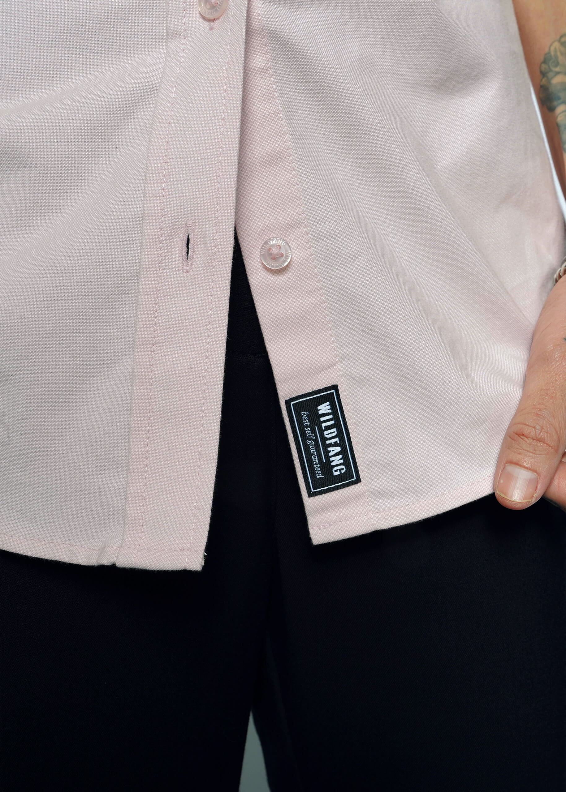 Detailed close-up of Wildfang branded placket label and branded buttons on the Essential Oxford Button Up in Blush