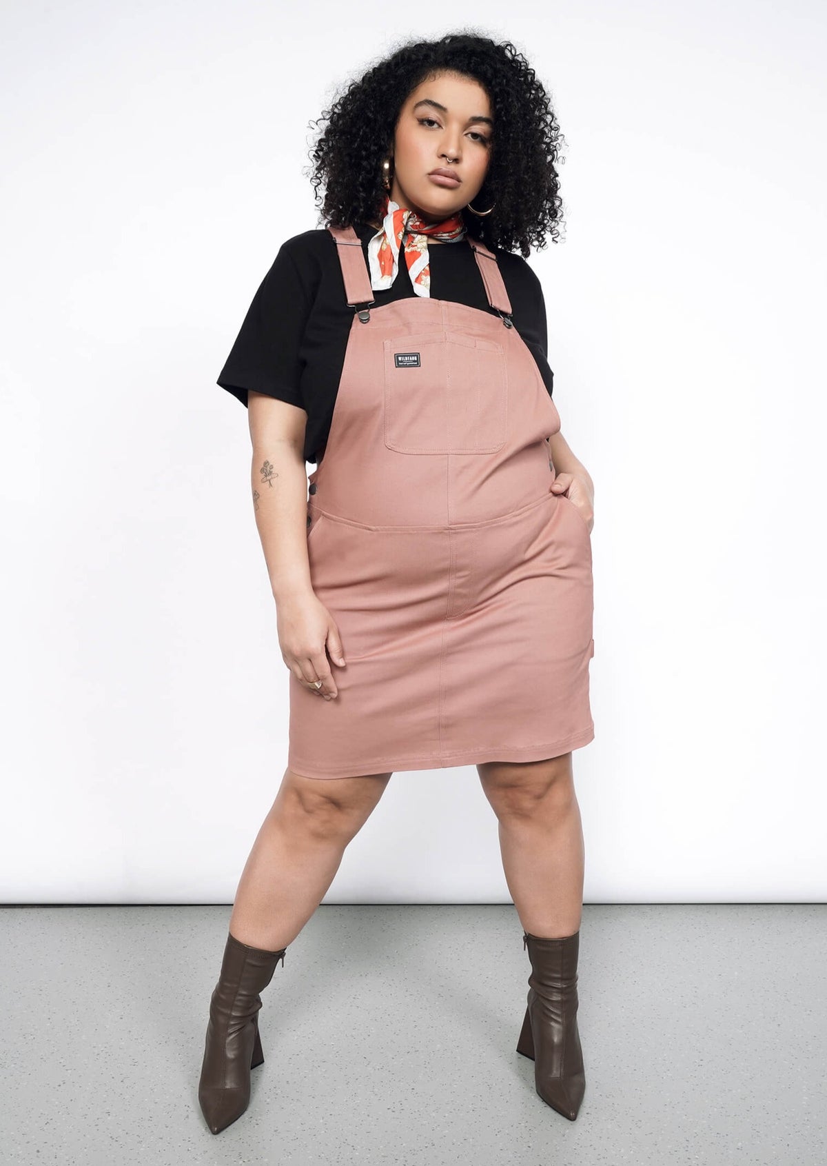 Model wearing the Essential Skirtall in Rose Brown in size XL with black T, red neck scarf and heeled ankle boots.