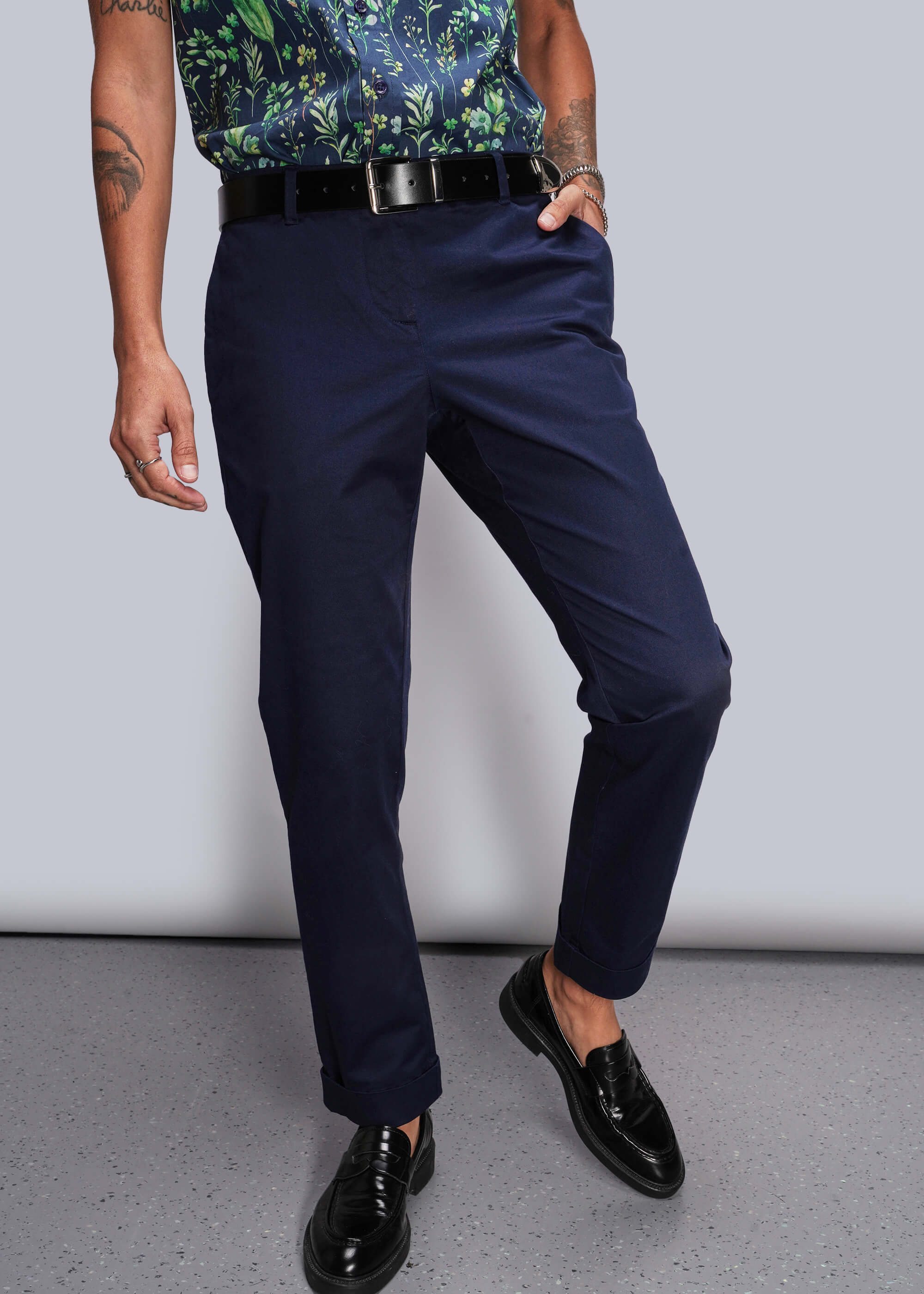 Person wearing navy pants and black shoes on a plain background