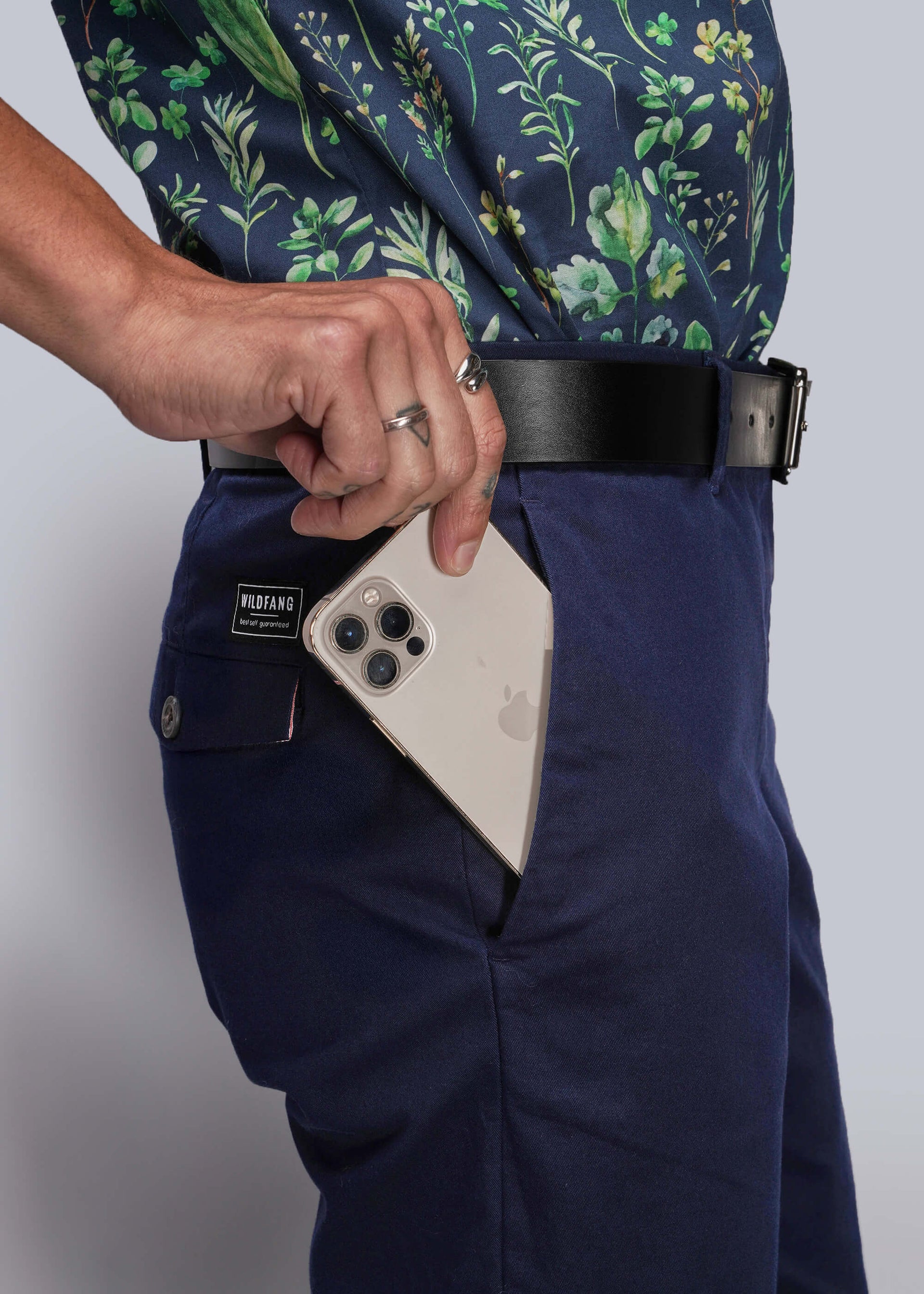 S=Person wearing navy pants with a floral shirt, holding an iPhone in a pocket.