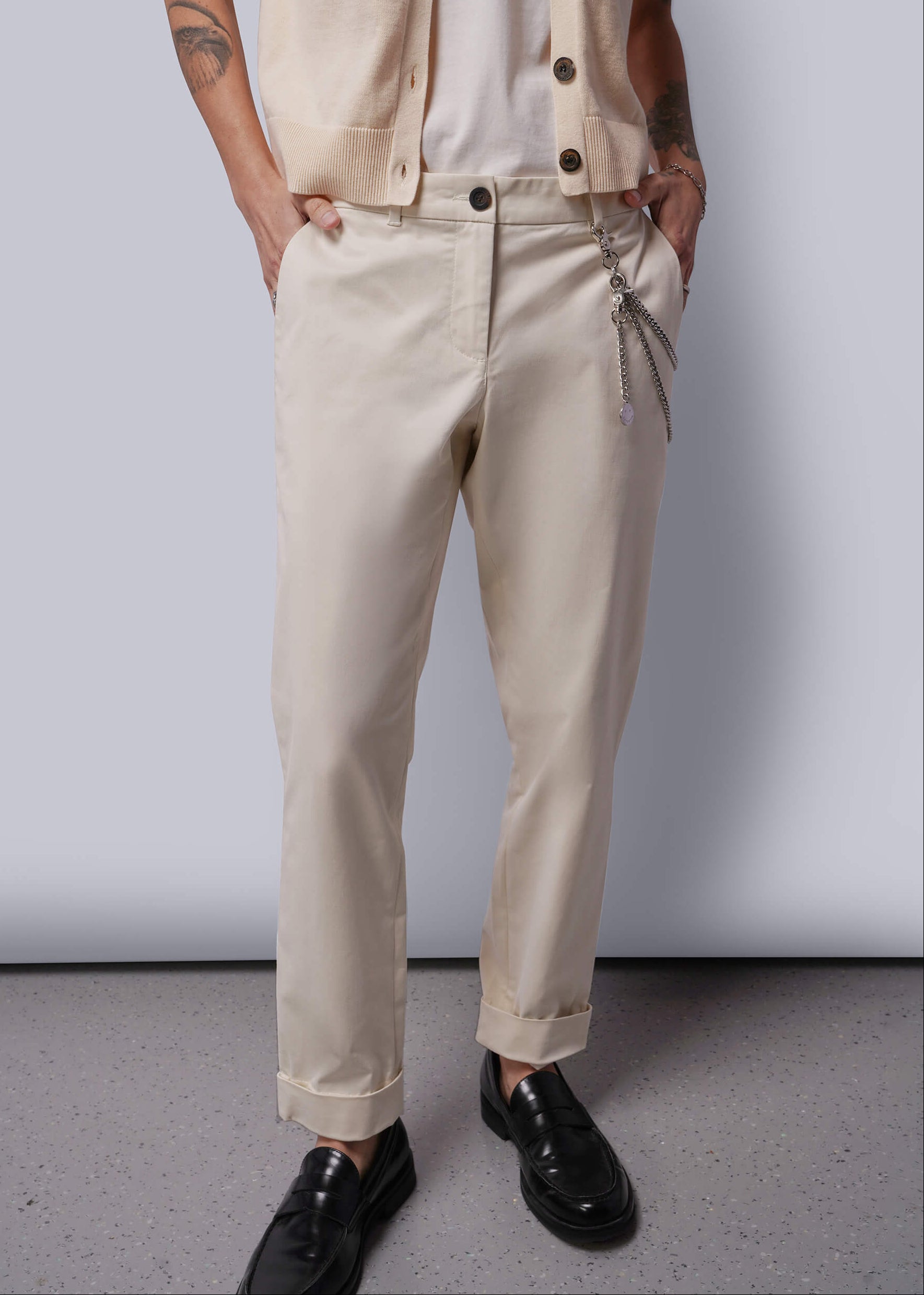 Person wearing beige pants and a vest against a plain background
