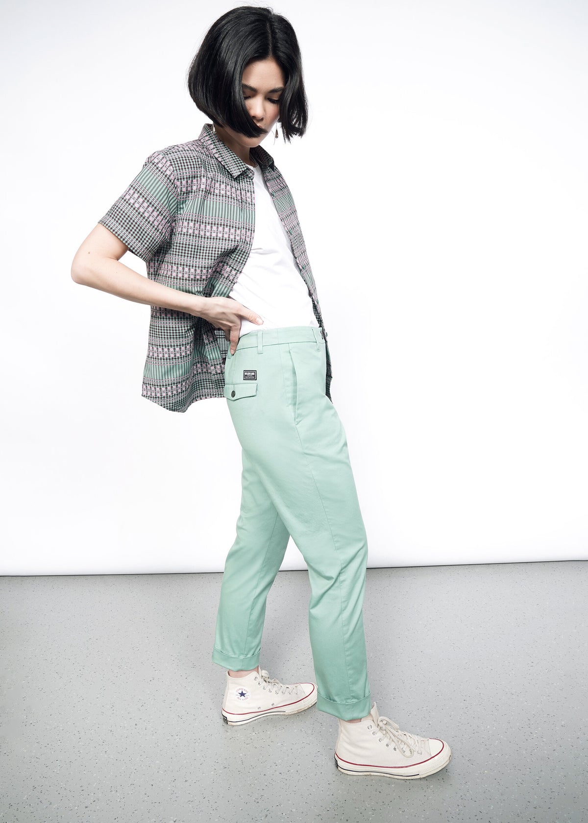 Side image of Model wearing the Essential Trouser in Sage in size 4, with a white T and the Essential Button Up in Gingham Sage