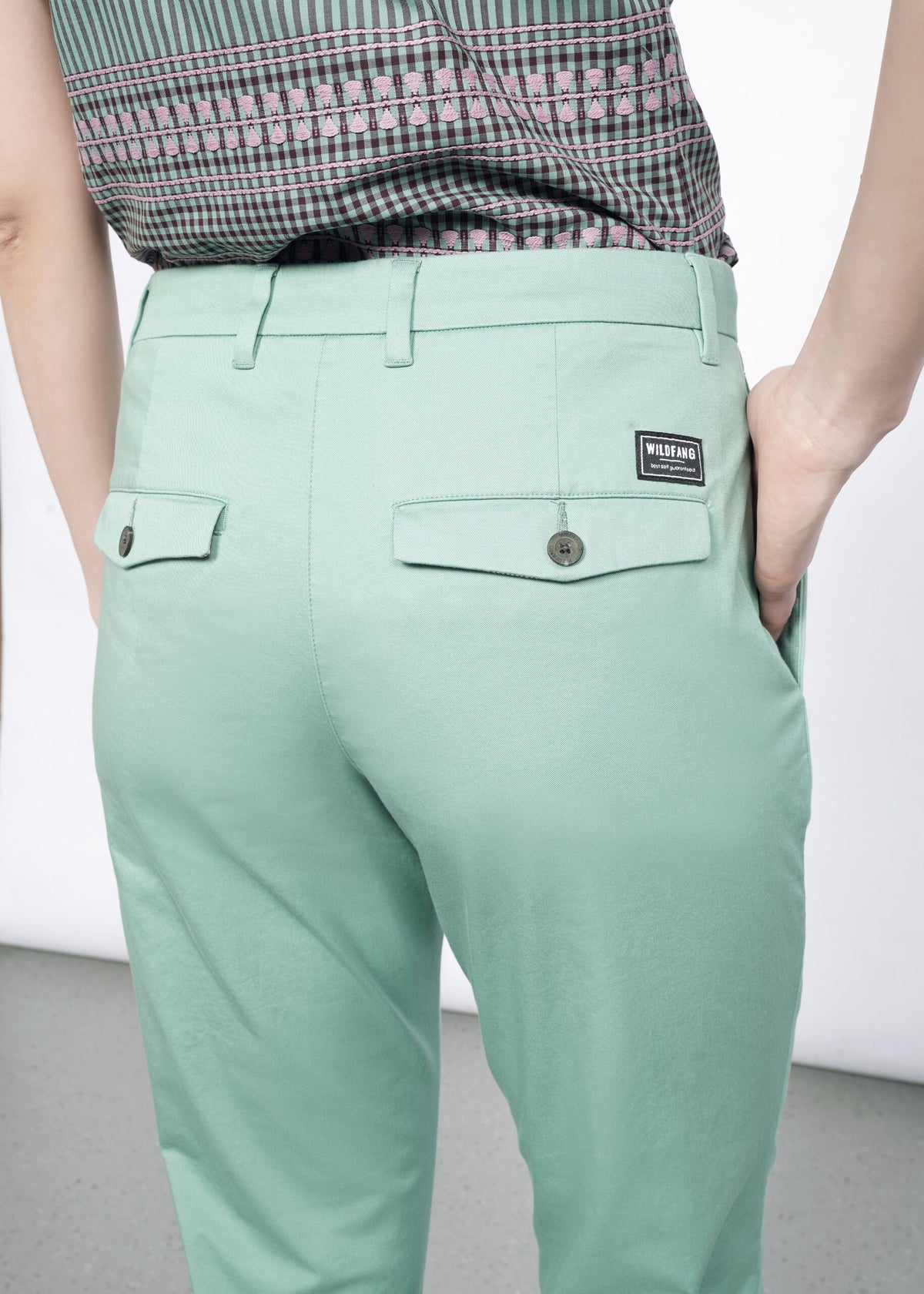 Close-up of Back image of Model wearing the Essential Trouser in Sage in size 4, with the Essential Button Up in Gingham Sage