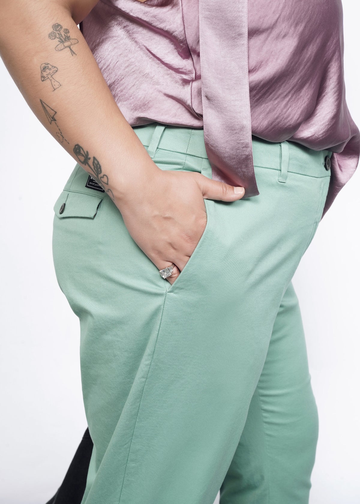 Close-up of Model wearing the Essential Trouser in Sage in size 16, with the Empower Cami in Mauve, with hand in side pocket.