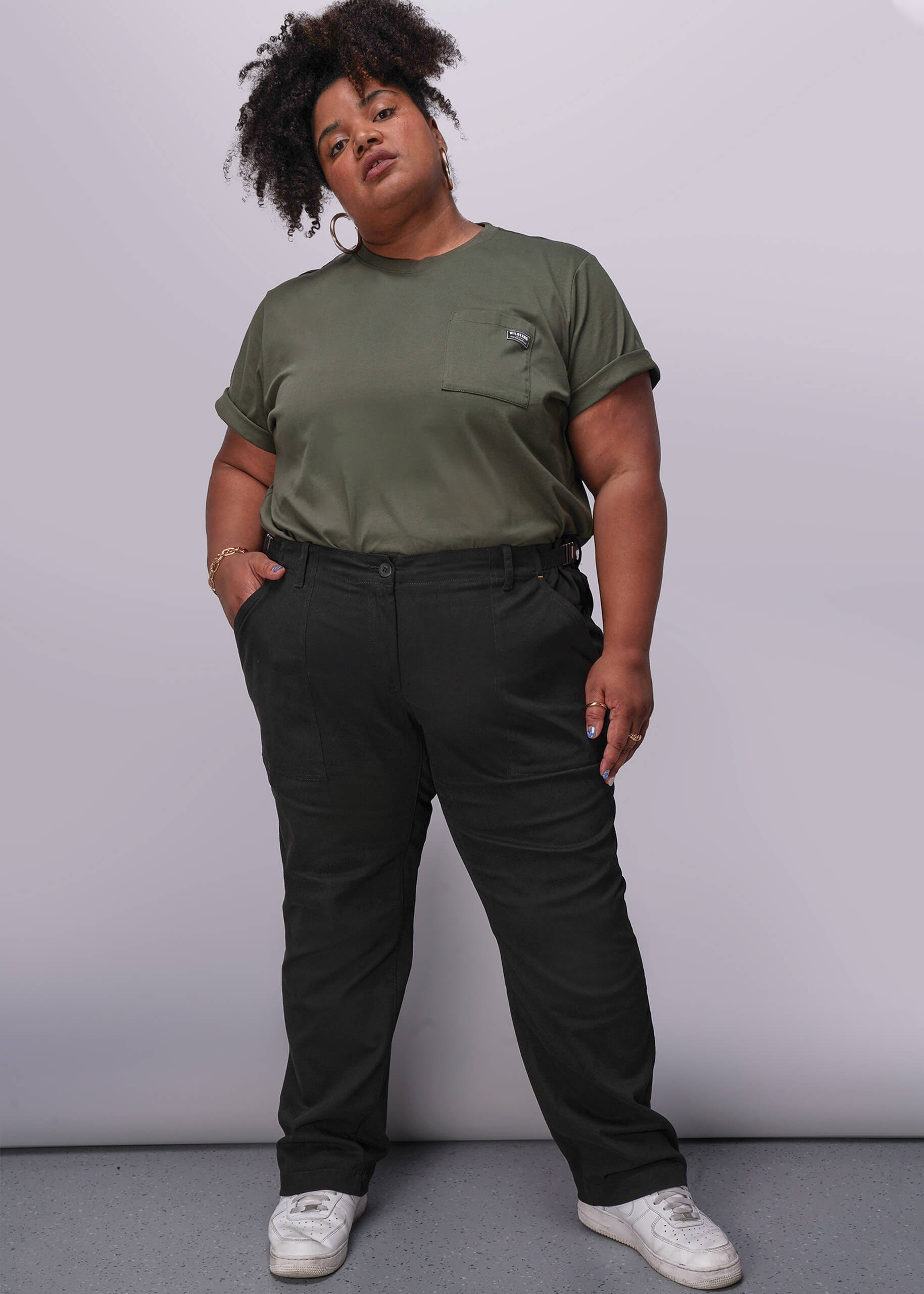 1X=Person wearing a green t-shirt and black pants against a plain background