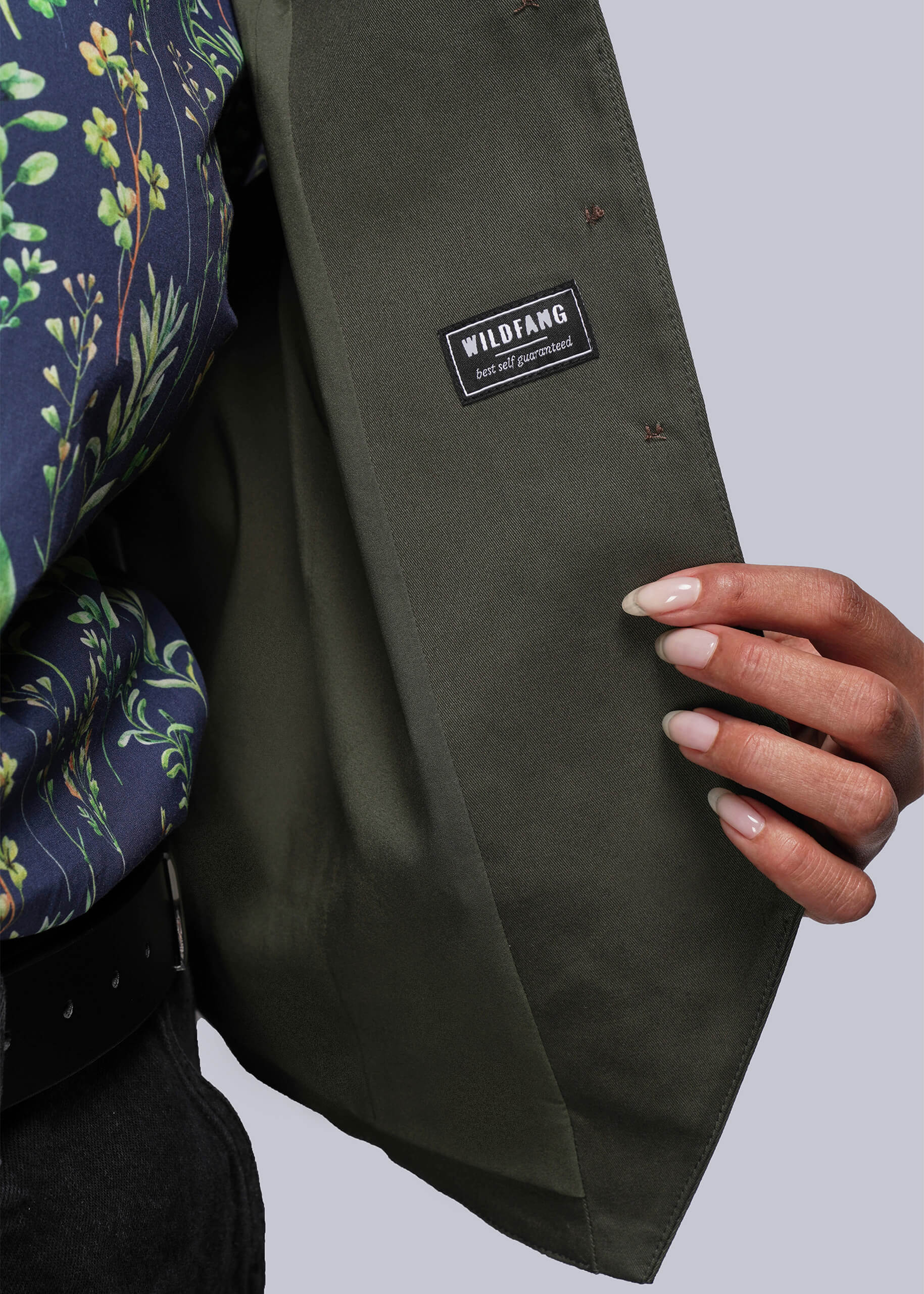 1X=Close up of person wearing a green vest with a visible brand label on a light gray background