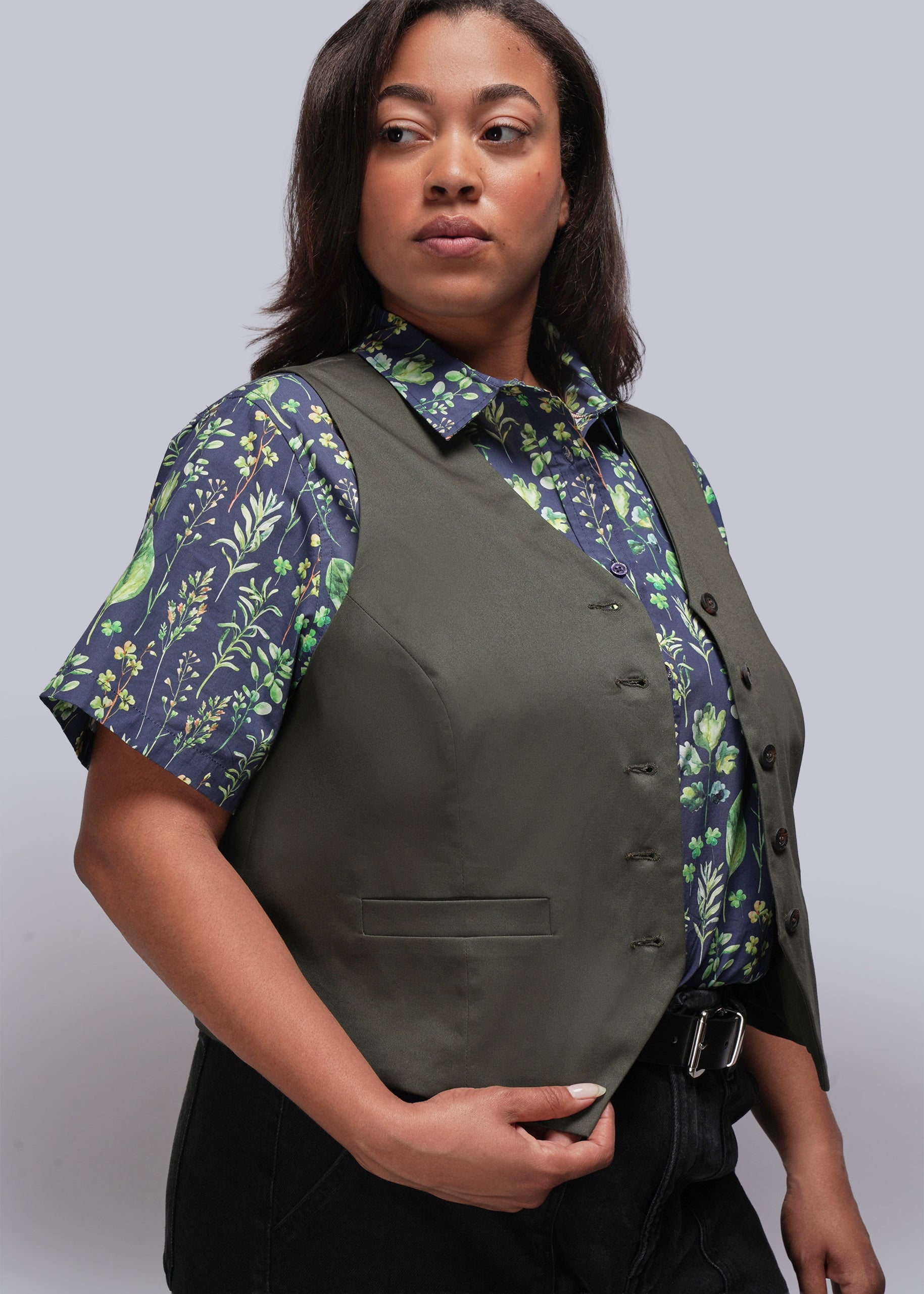 1X=Person wearing a green vest over a leaf print shirt on a gray background