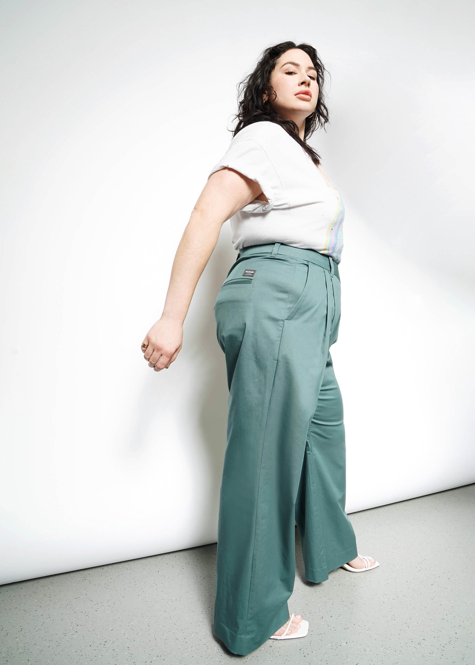Side full body shot of extended sizing model in Wildfang Essential Wide Leg Trouser in Dark Teal, styled with short sleeve white t-shirt