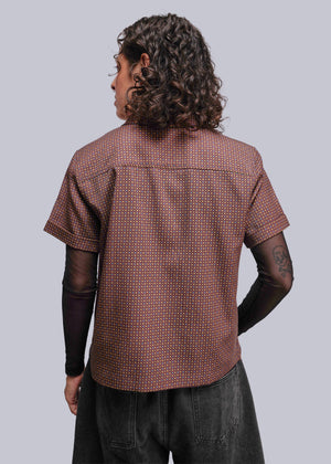 S=Person wearing a brown patterned shirt from behind on a light gray background