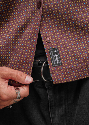 S=Close-up of a patterned shirt with a visible brand label, held by a hand.