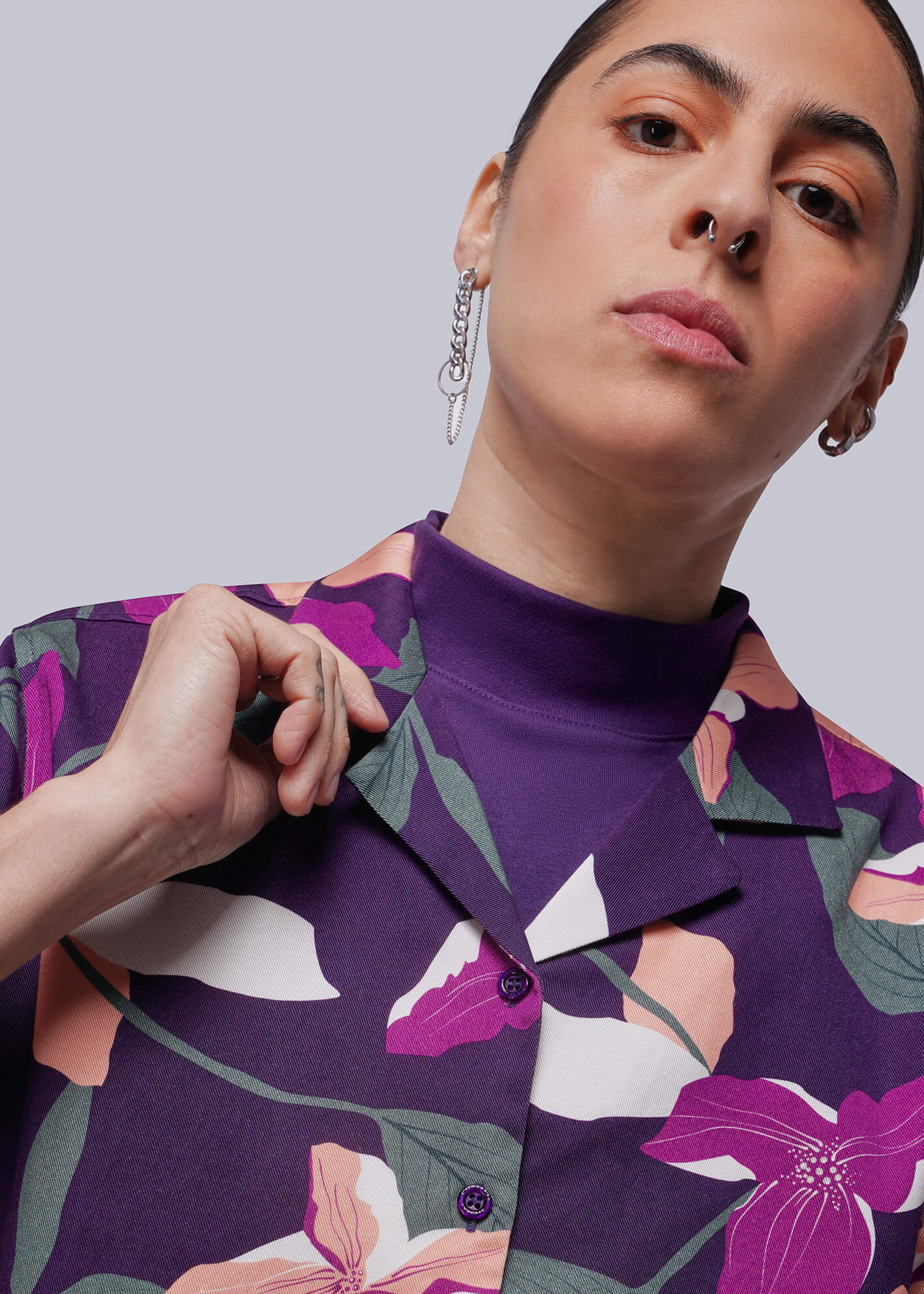 Person wearing a purple floral patterned shirt against a plain background