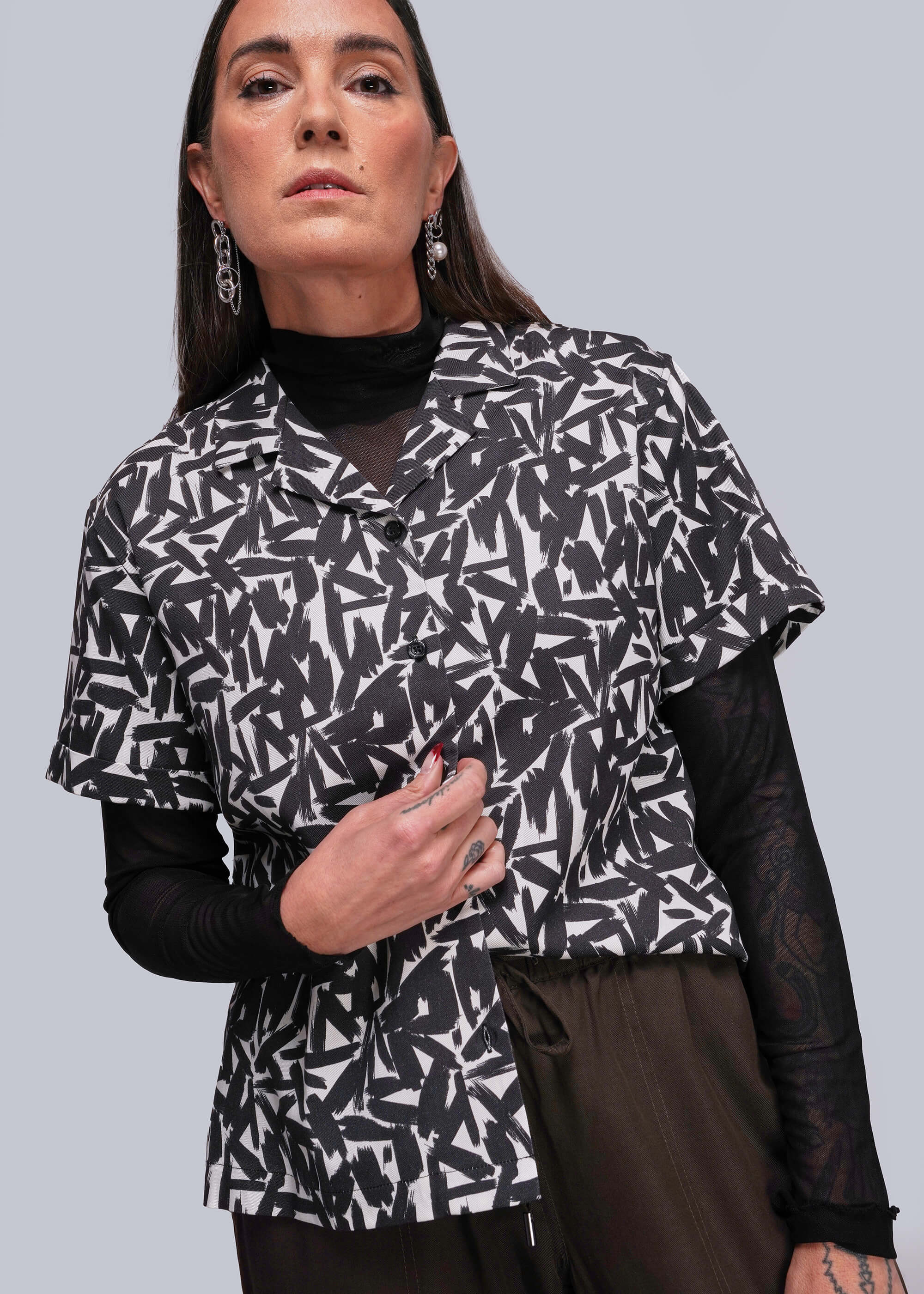 Woman wearing a black and white patterned jacket against a gray background
