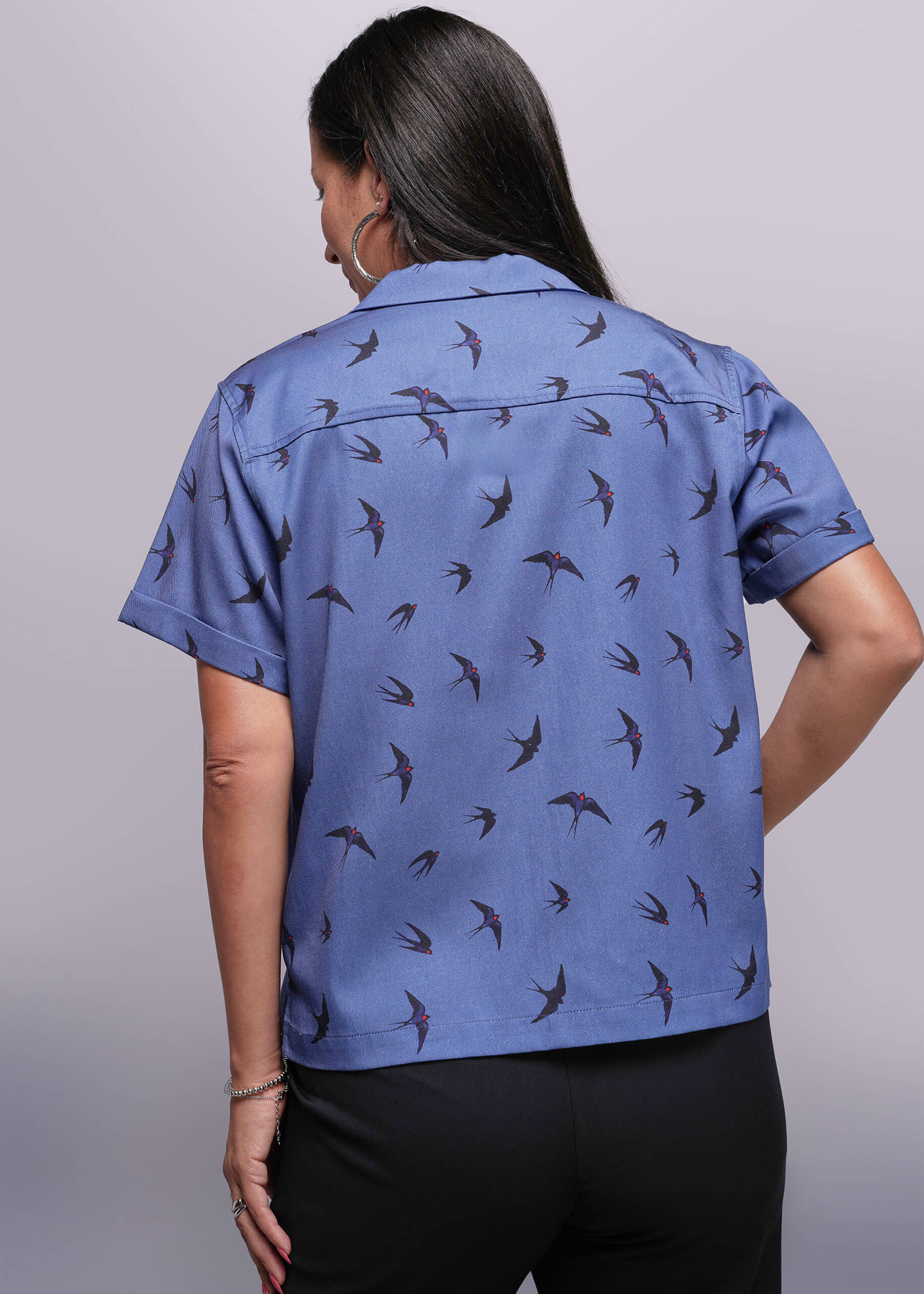 S=Back of person wearing a blue shirt with bird pattern on a plain background