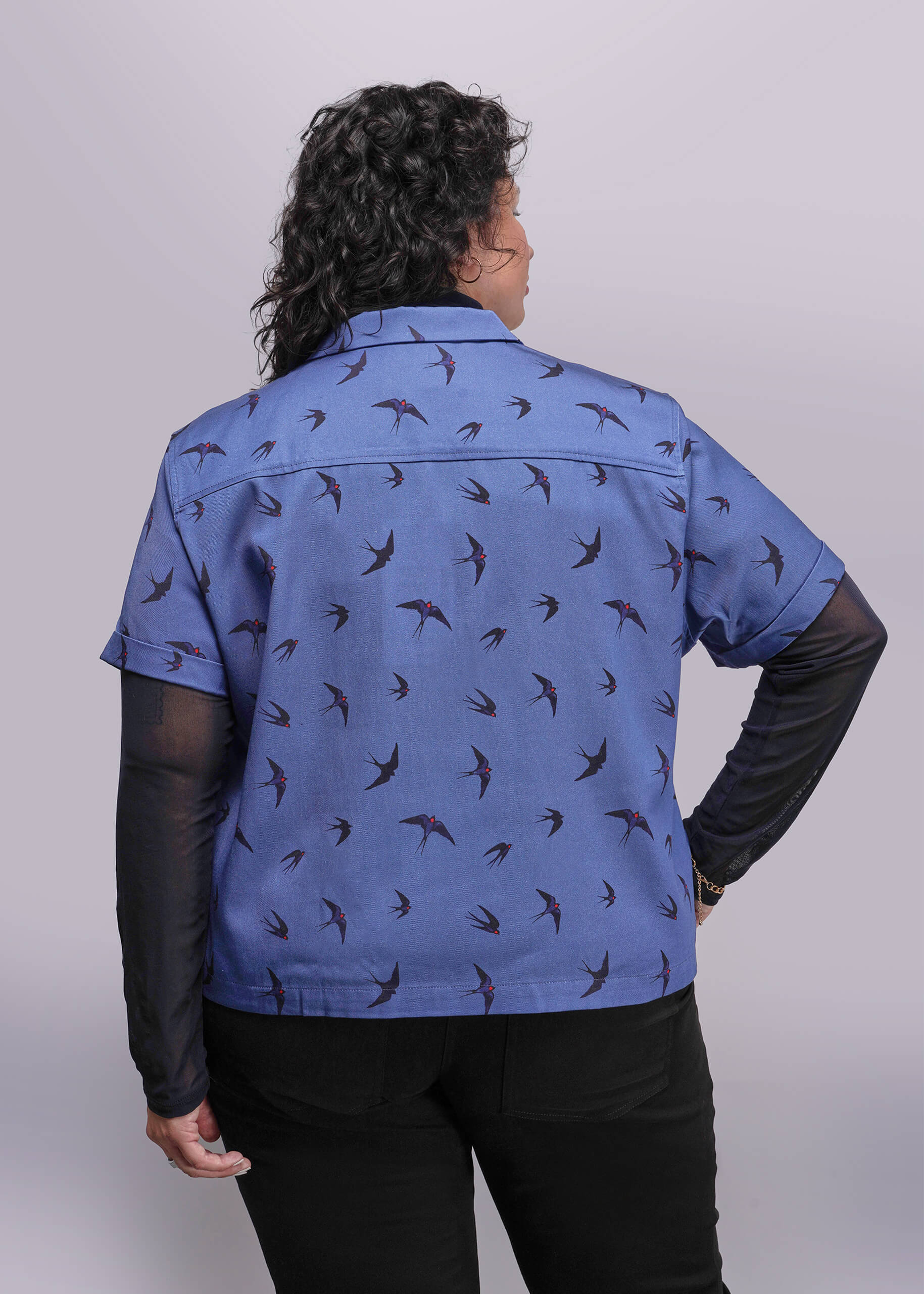 1X=Person wearing a blue jacket with bird pattern on a plain background