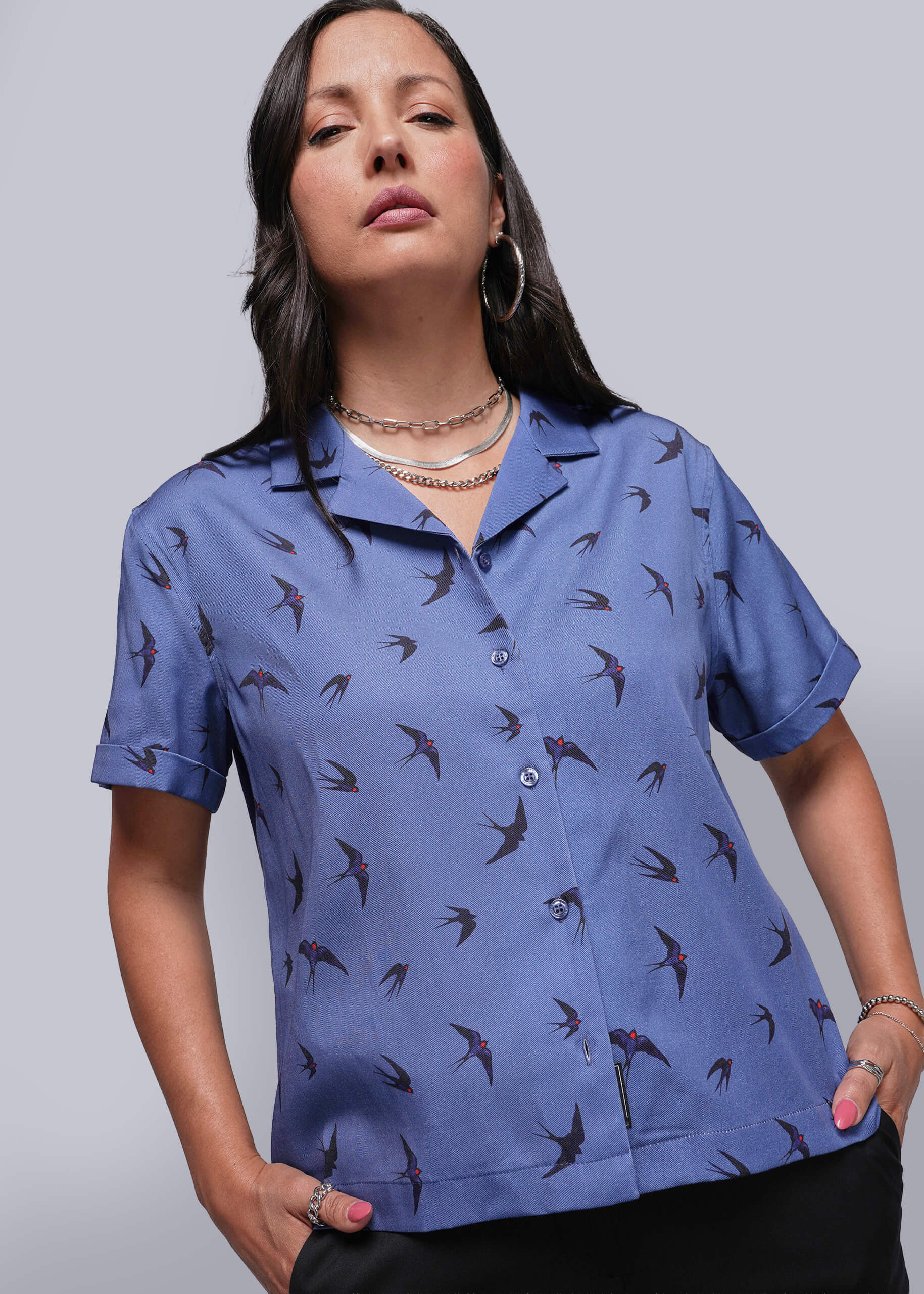 Woman wearing a blue shirt with bird pattern against a plain background