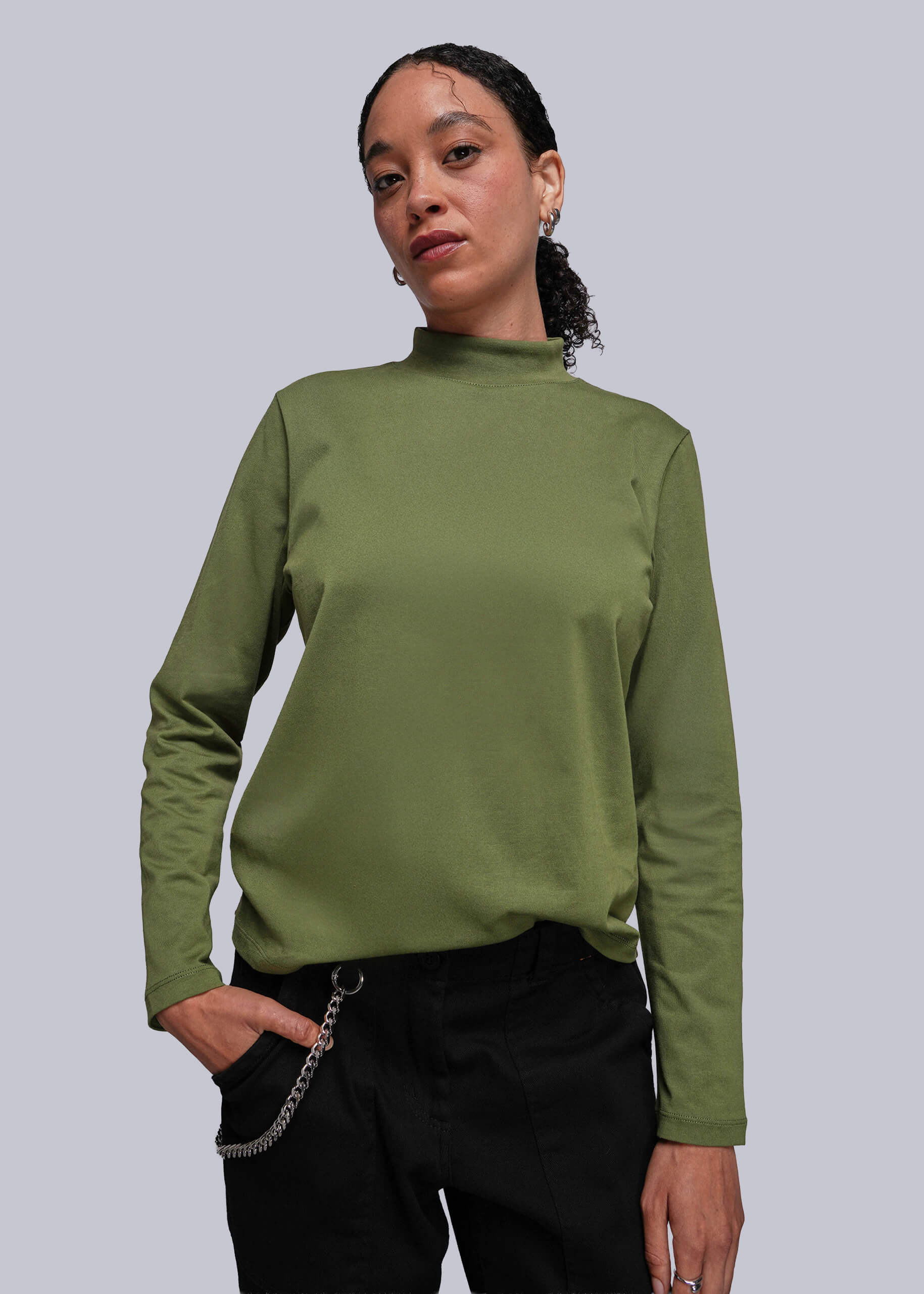 Person wearing a green long-sleeve top against a plain background