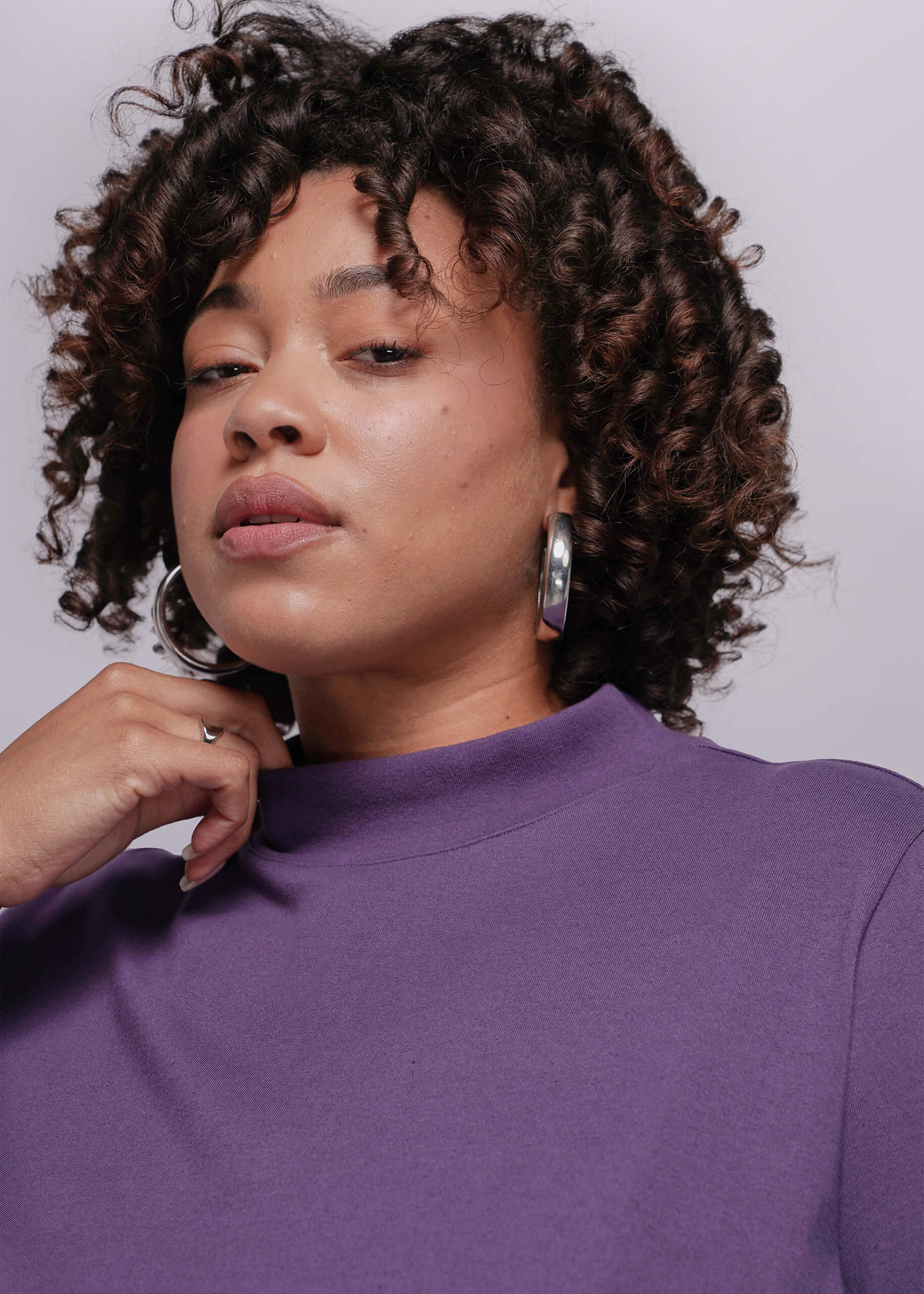 1X=Woman wearing a purple top with a plain background