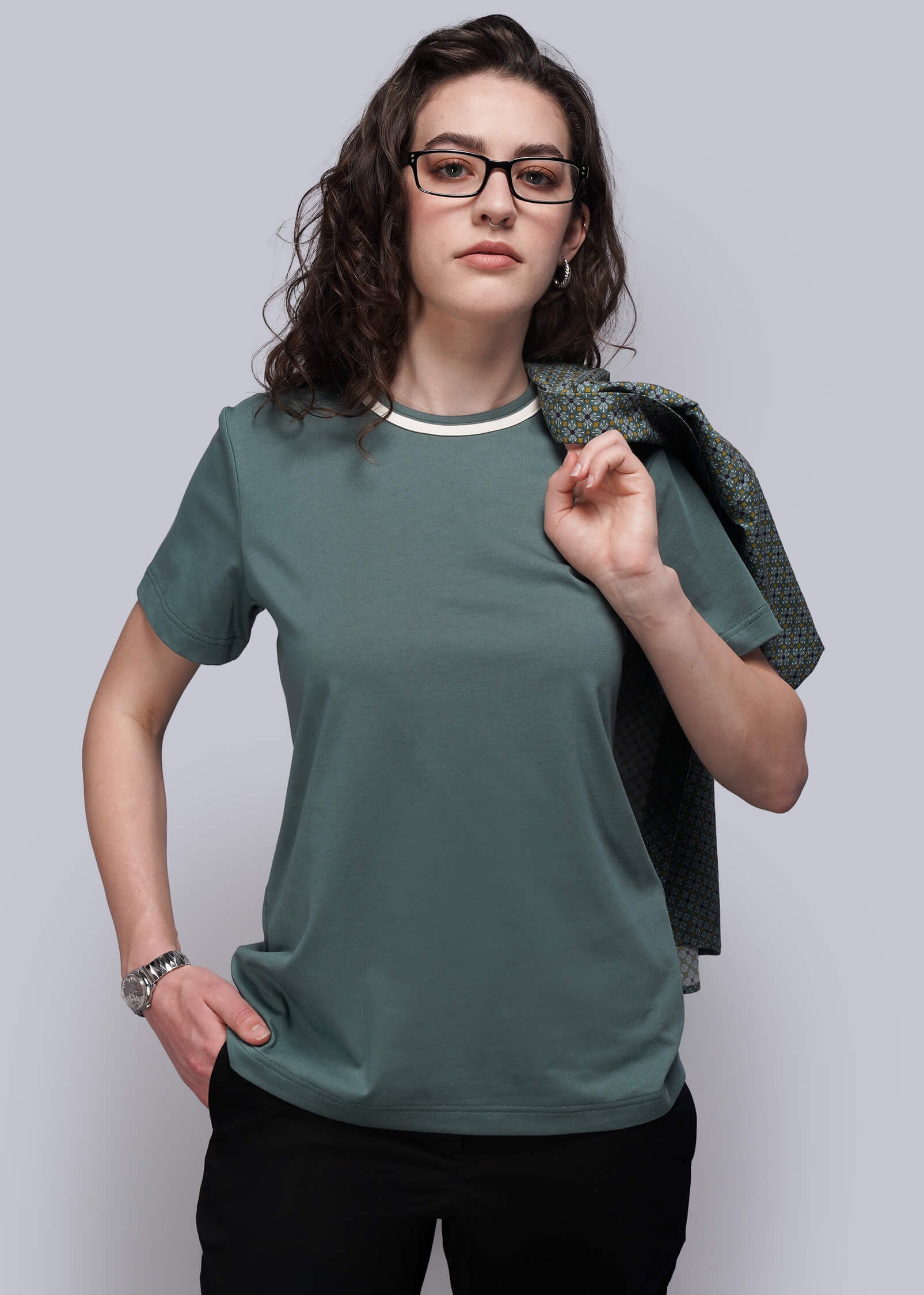 S=Woman wearing a green t-shirt and black pants against a plain background