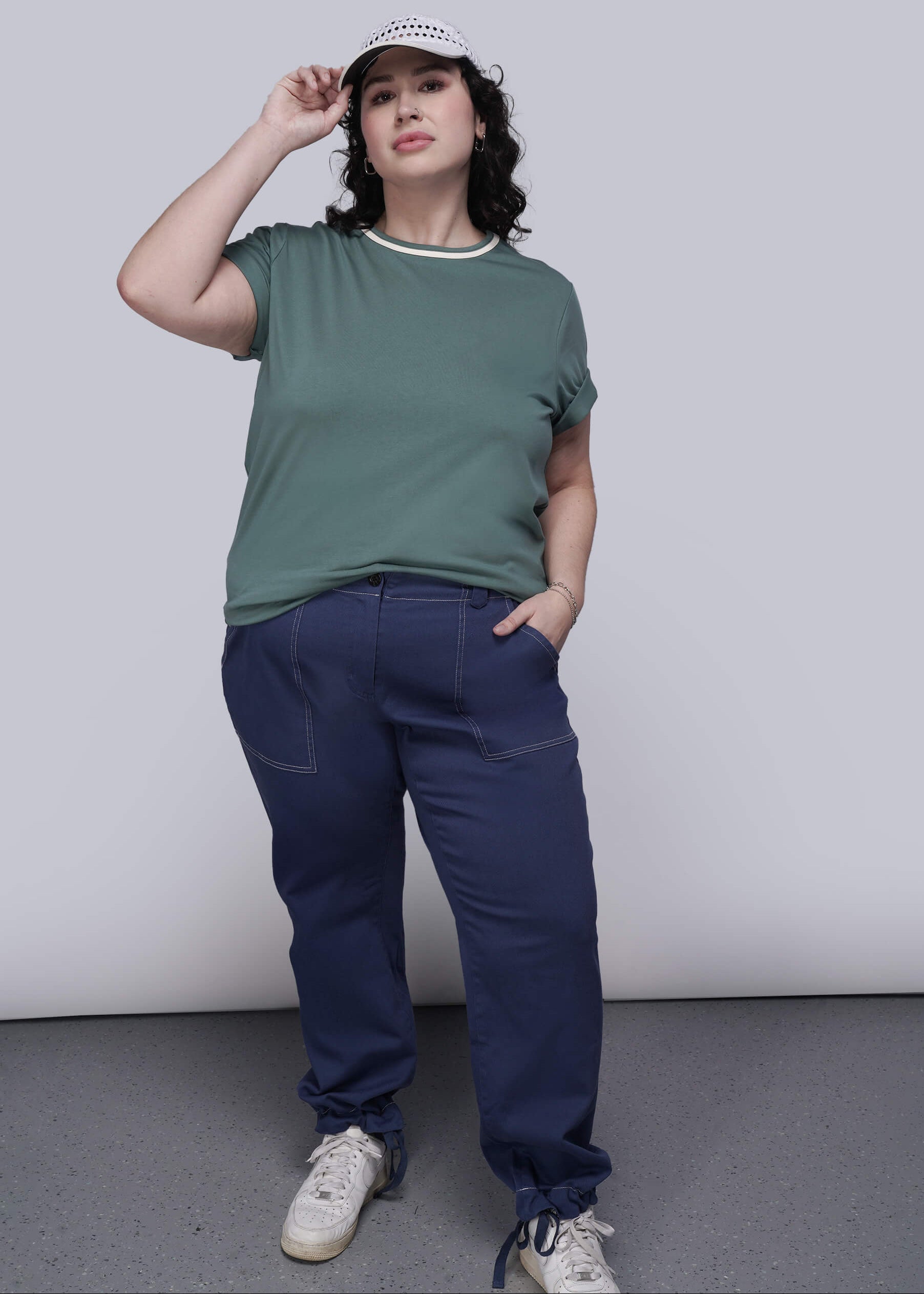 1X=Person wearing a green t-shirt and blue pants against a plain background