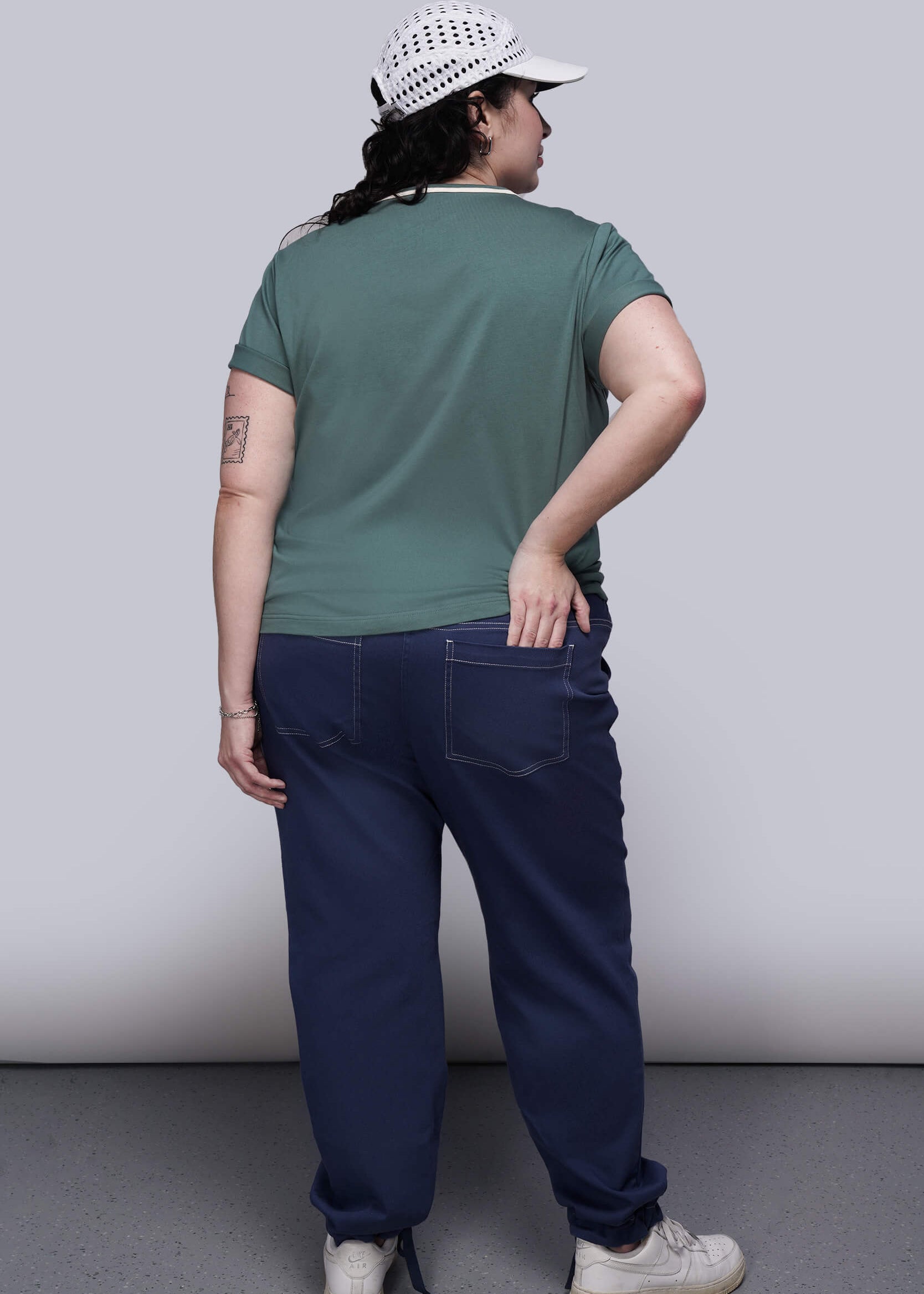 1X=Person wearing a green t-shirt and blue pants against a plain background