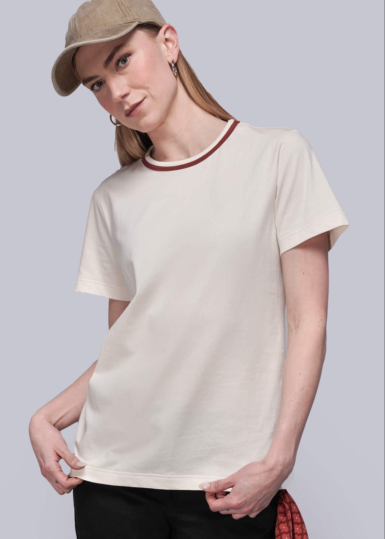 S=Person wearing a beige t-shirt, black pants, and a cap on a plain background