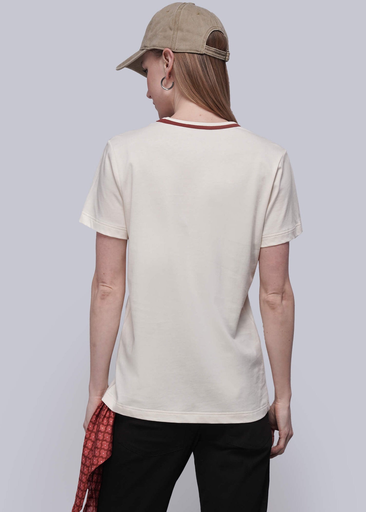 S=Person wearing a beige t-shirt, black pants, and a cap on a plain background