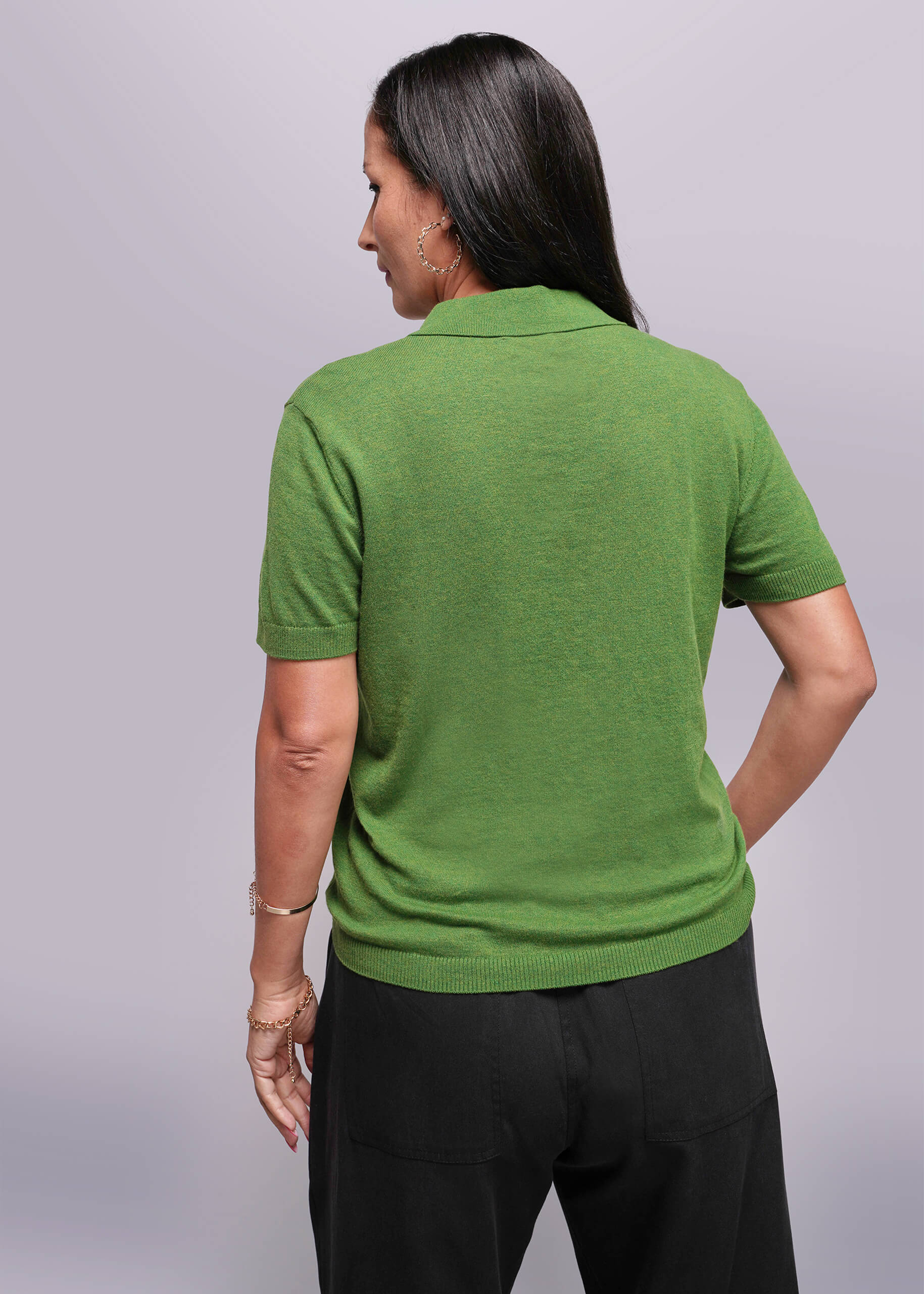 S=Person wearing a green polo shirt and black pants on a gray background