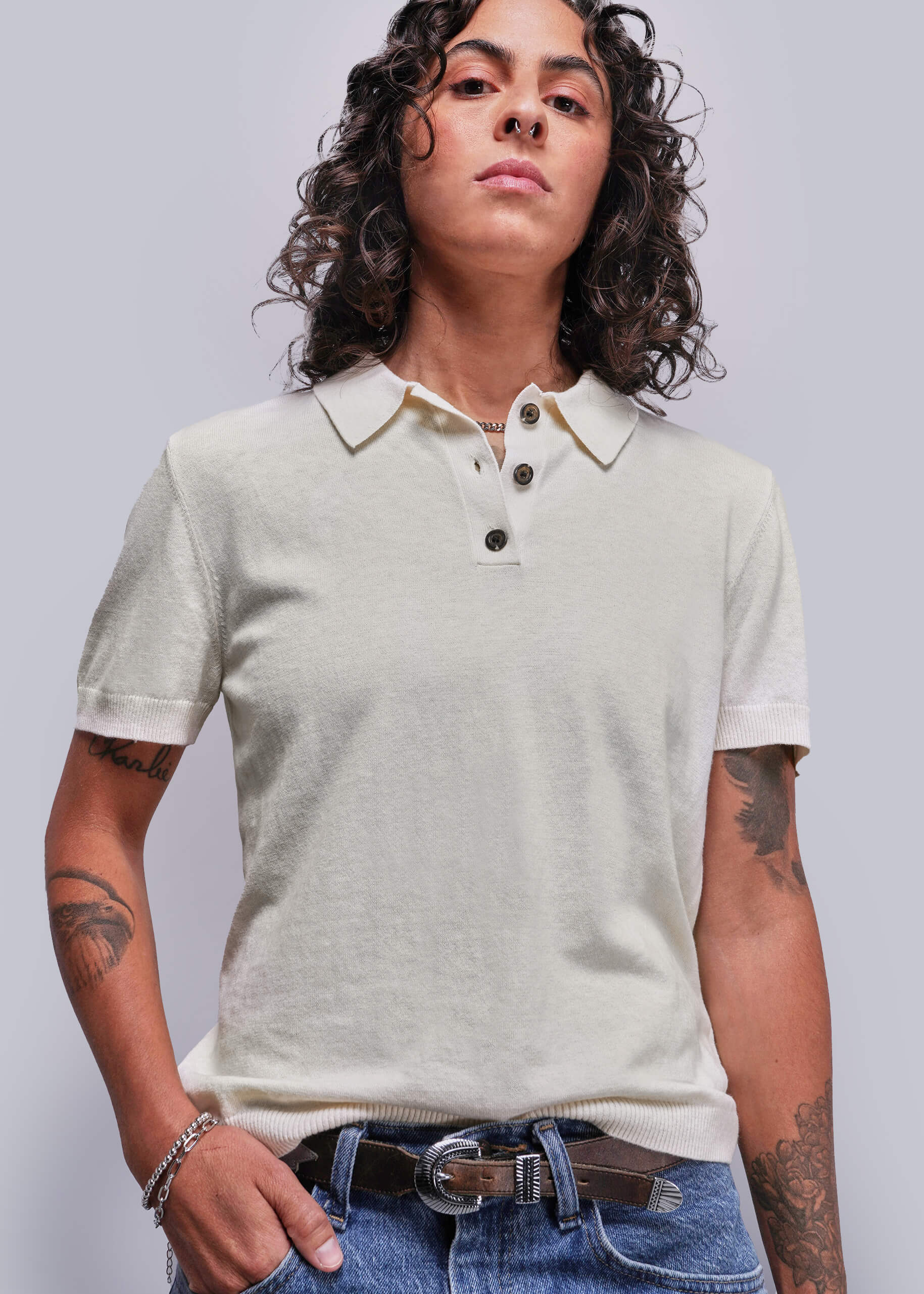 Person wearing a light-colored polo shirt and jeans against a plain background